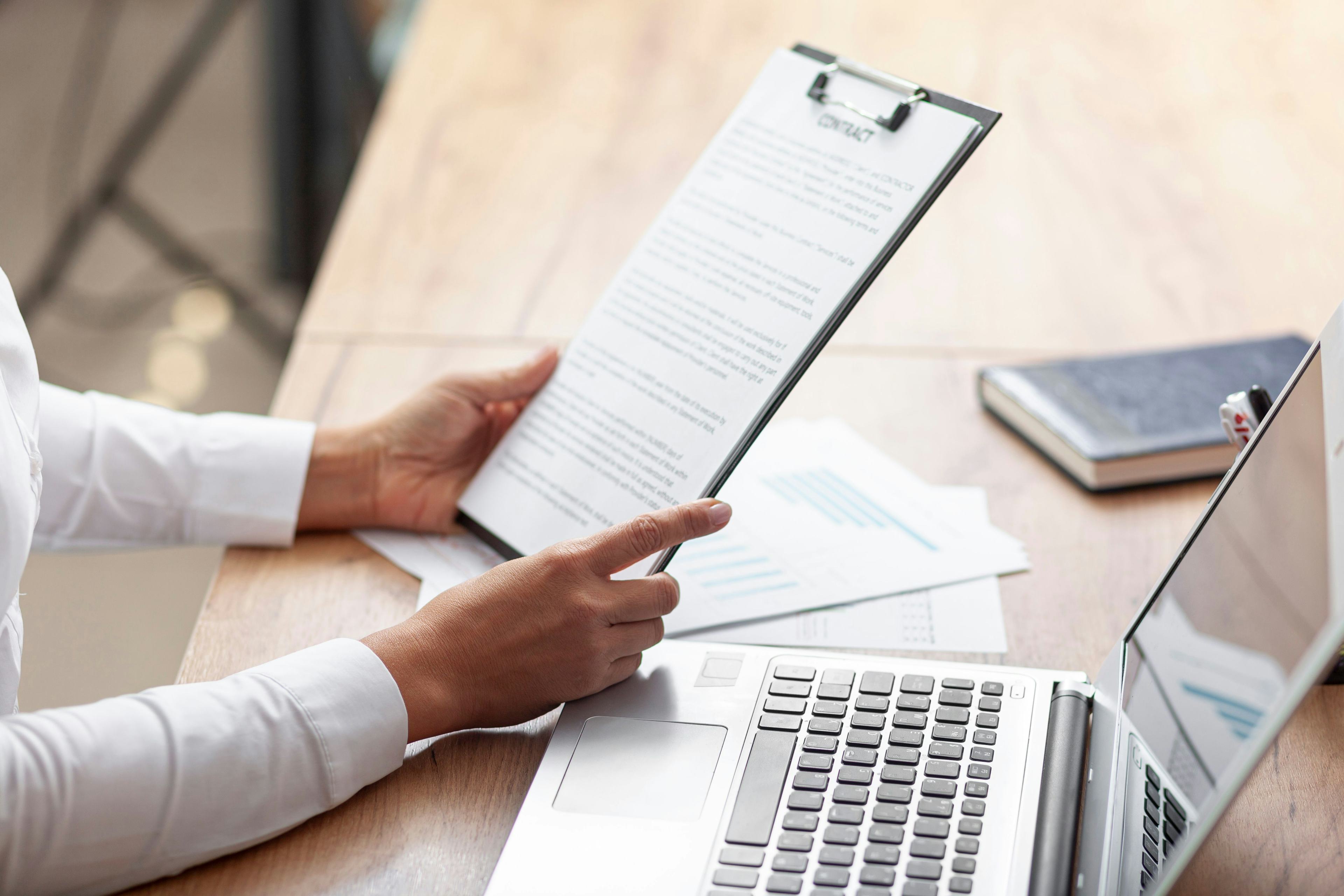 professional viewing clipboard of paperwork and using laptop