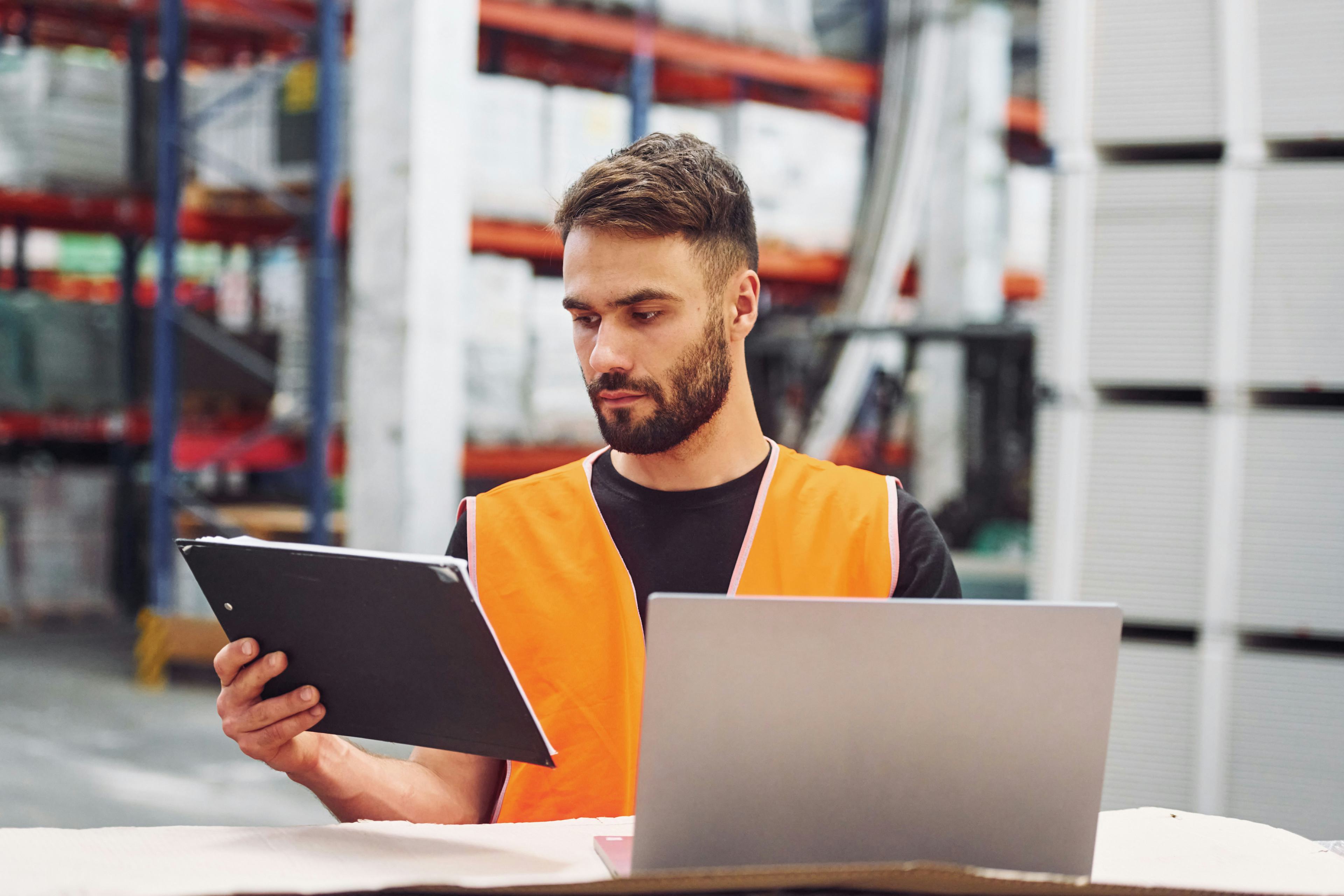 warehouse storage worker holding a tablet with laptop open