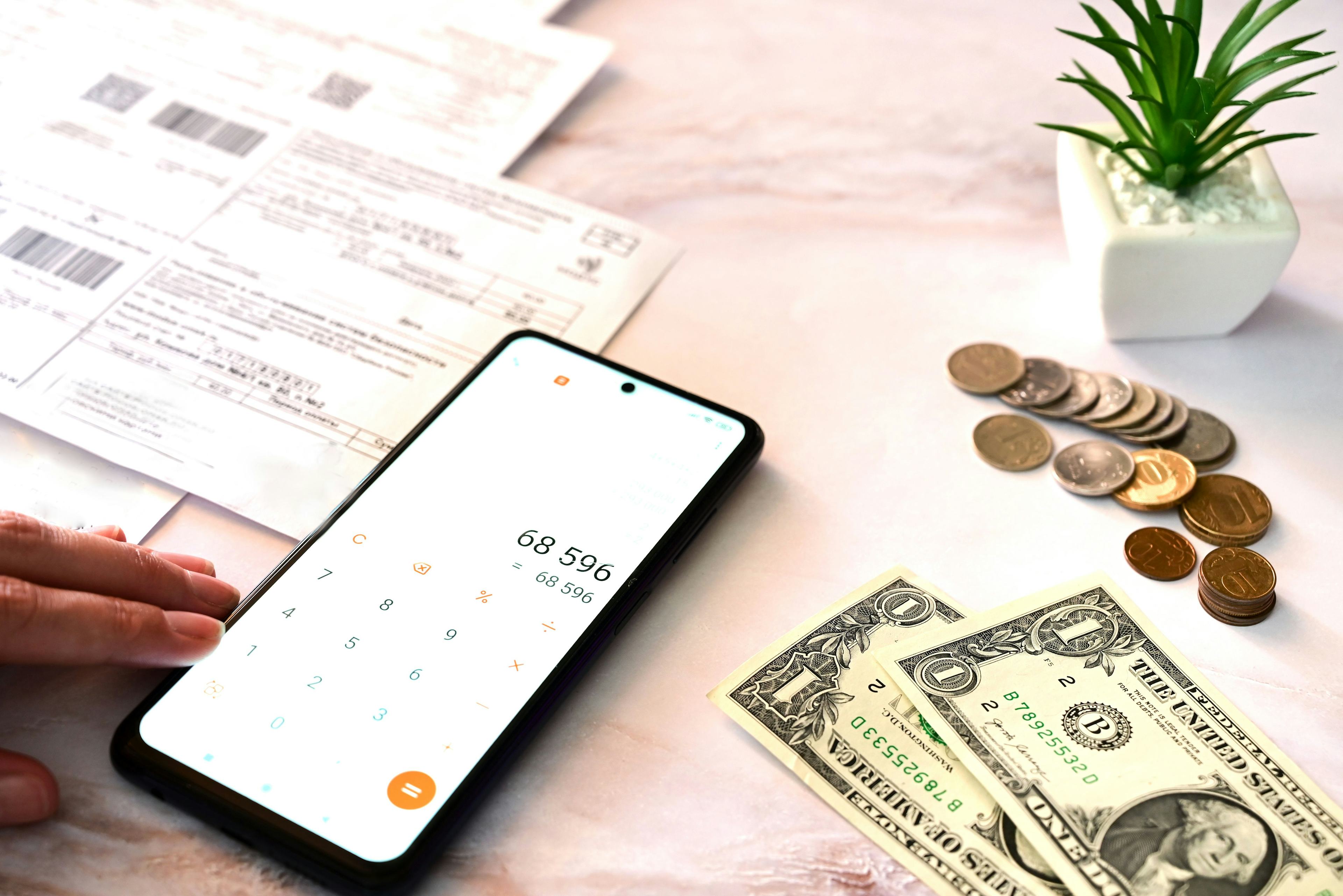 calculator app on phone screen with money on counter beside phone