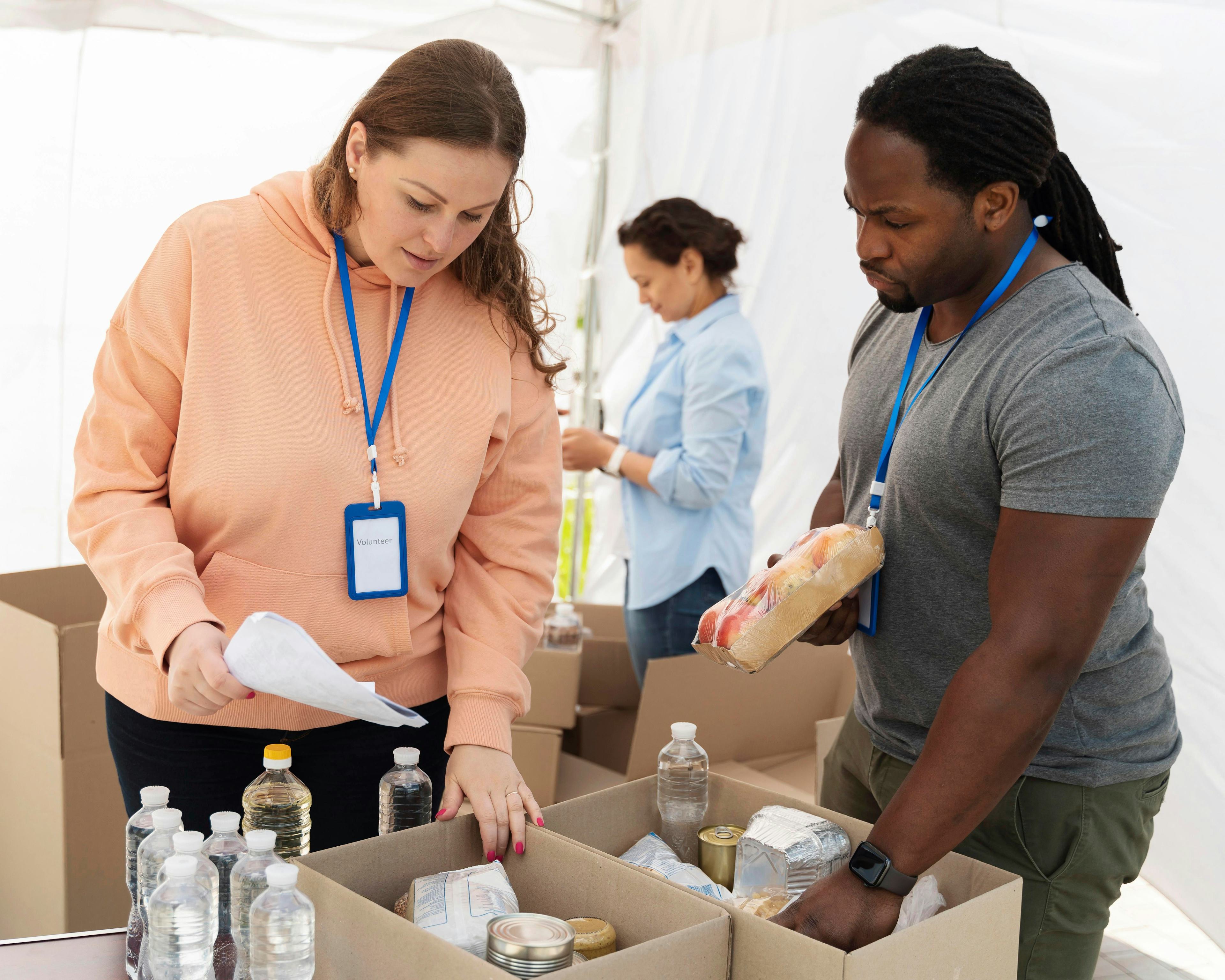 two workers at a food bank organizing items into cardboard boxes