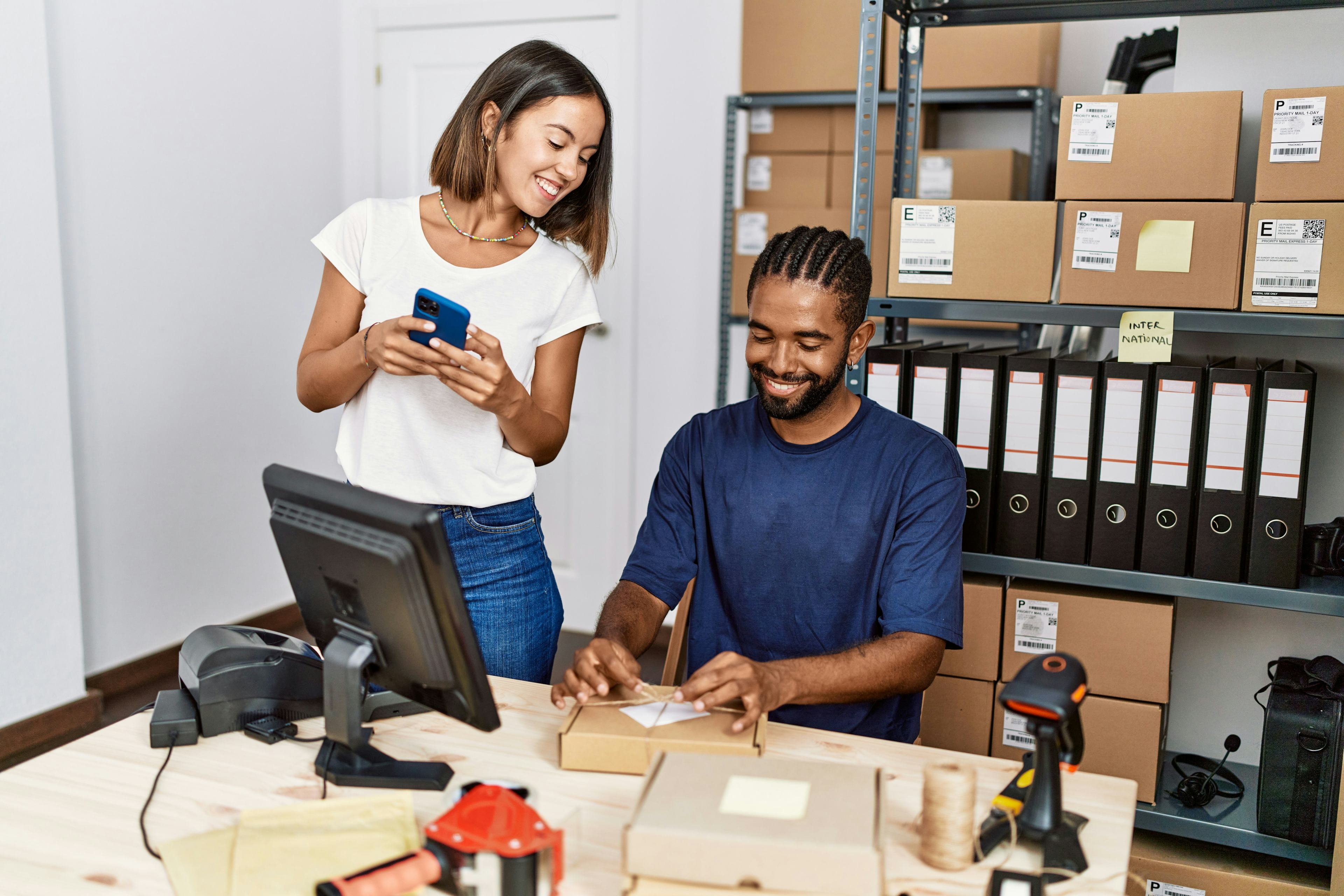 people viewing and smiling at package while working together in a room with unopened packages