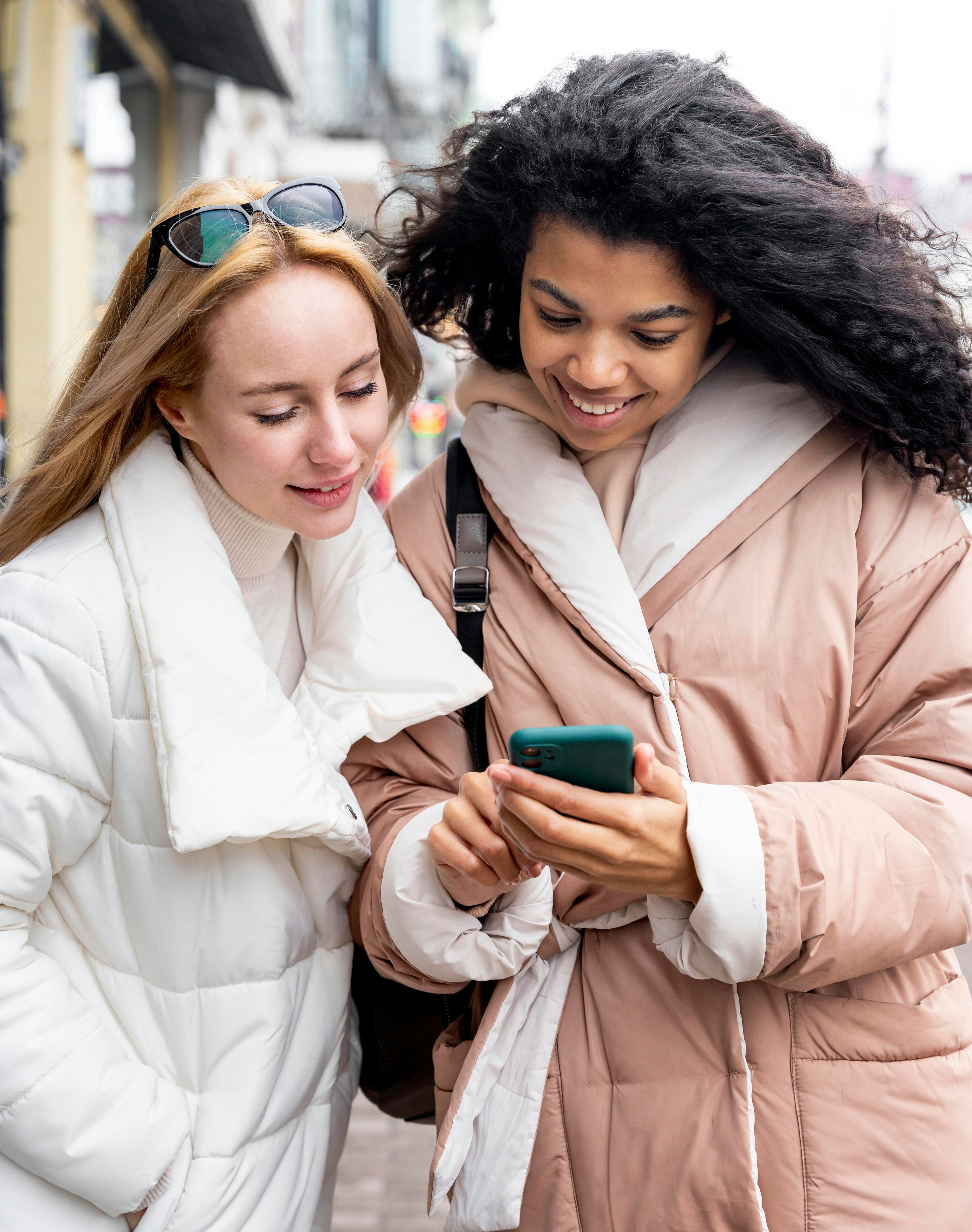 Medium shot women looking at smartphone