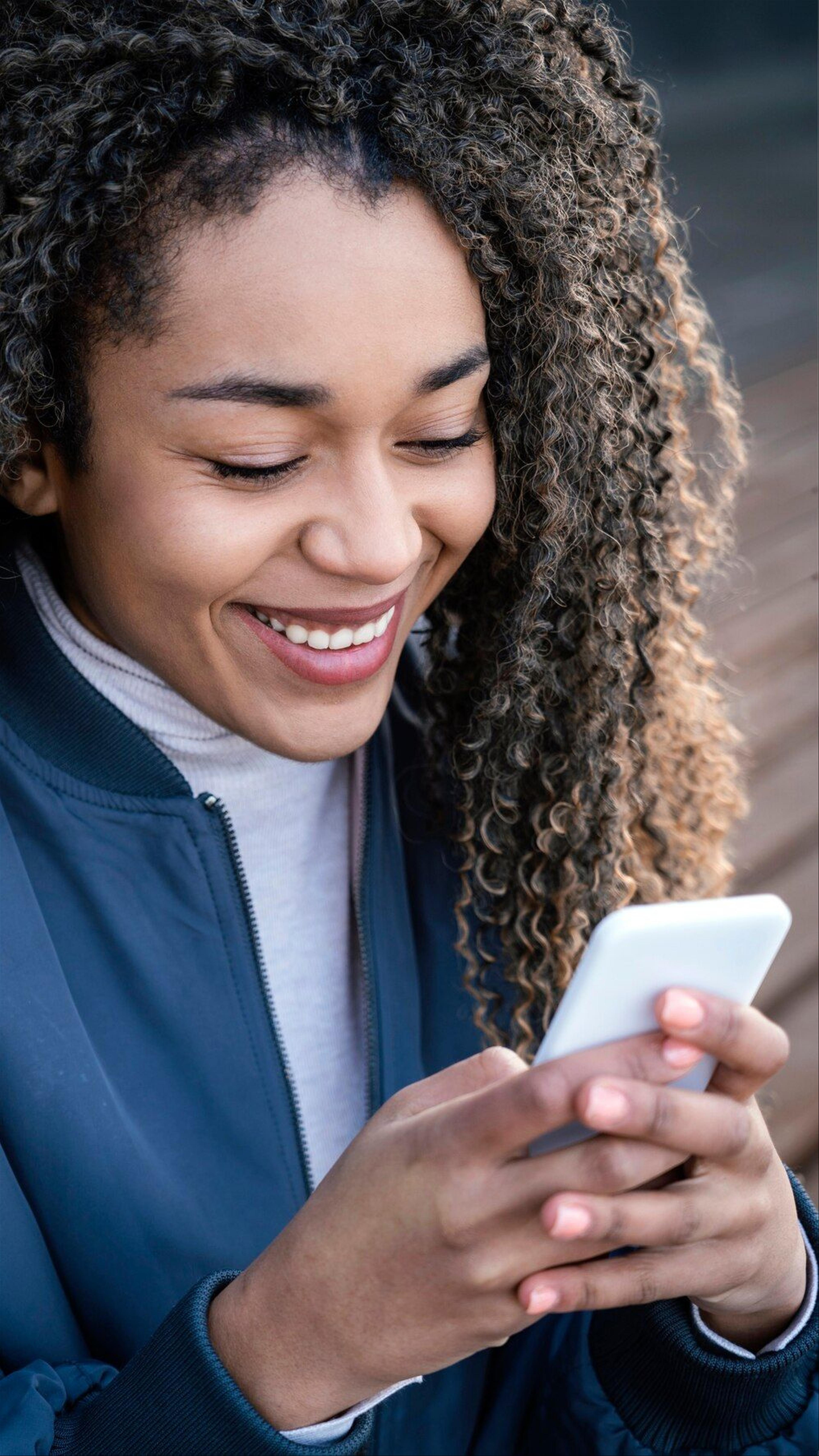 woman smiling while holding mobile phone