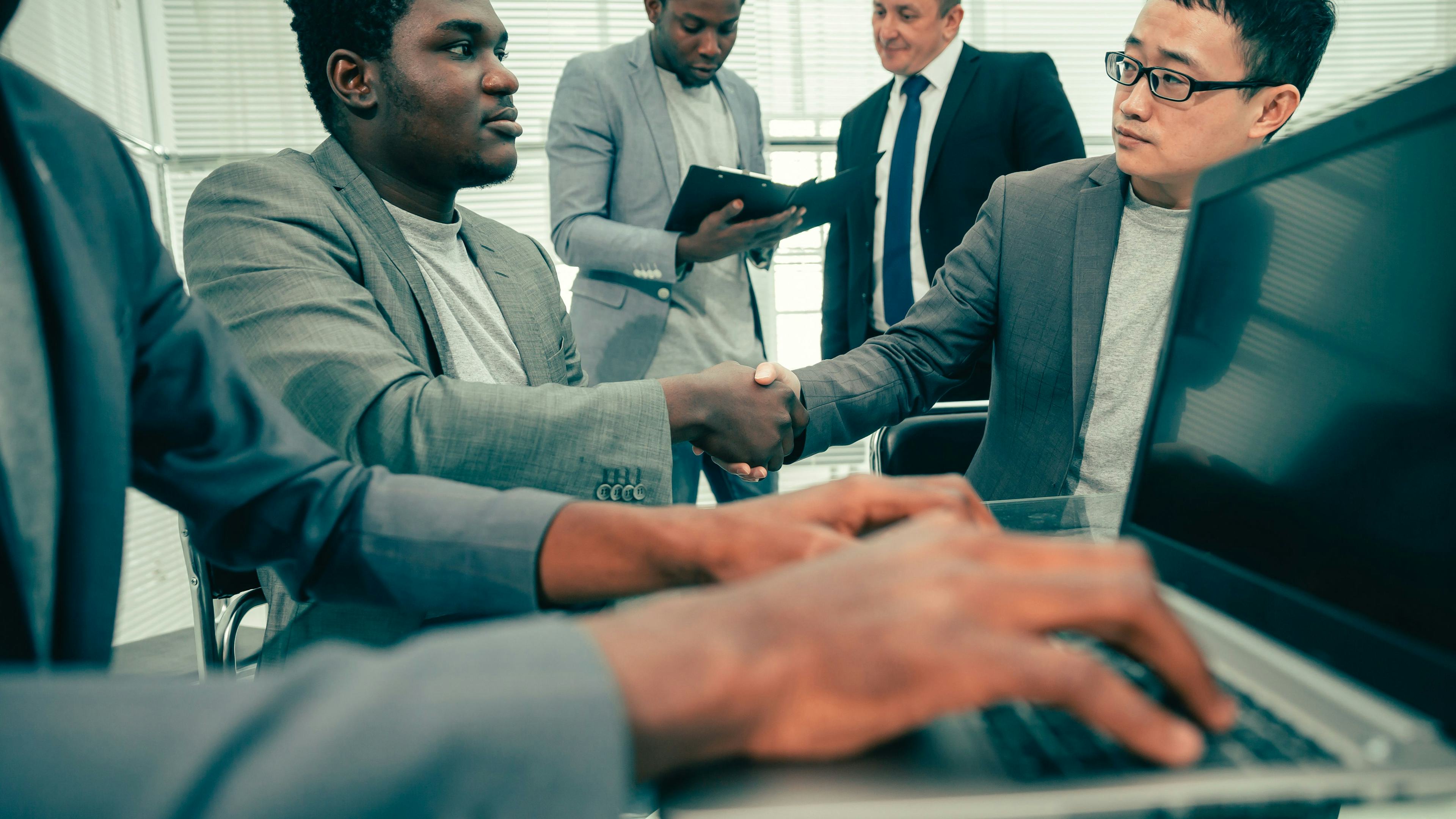 multiple business people talking and one working on a computer