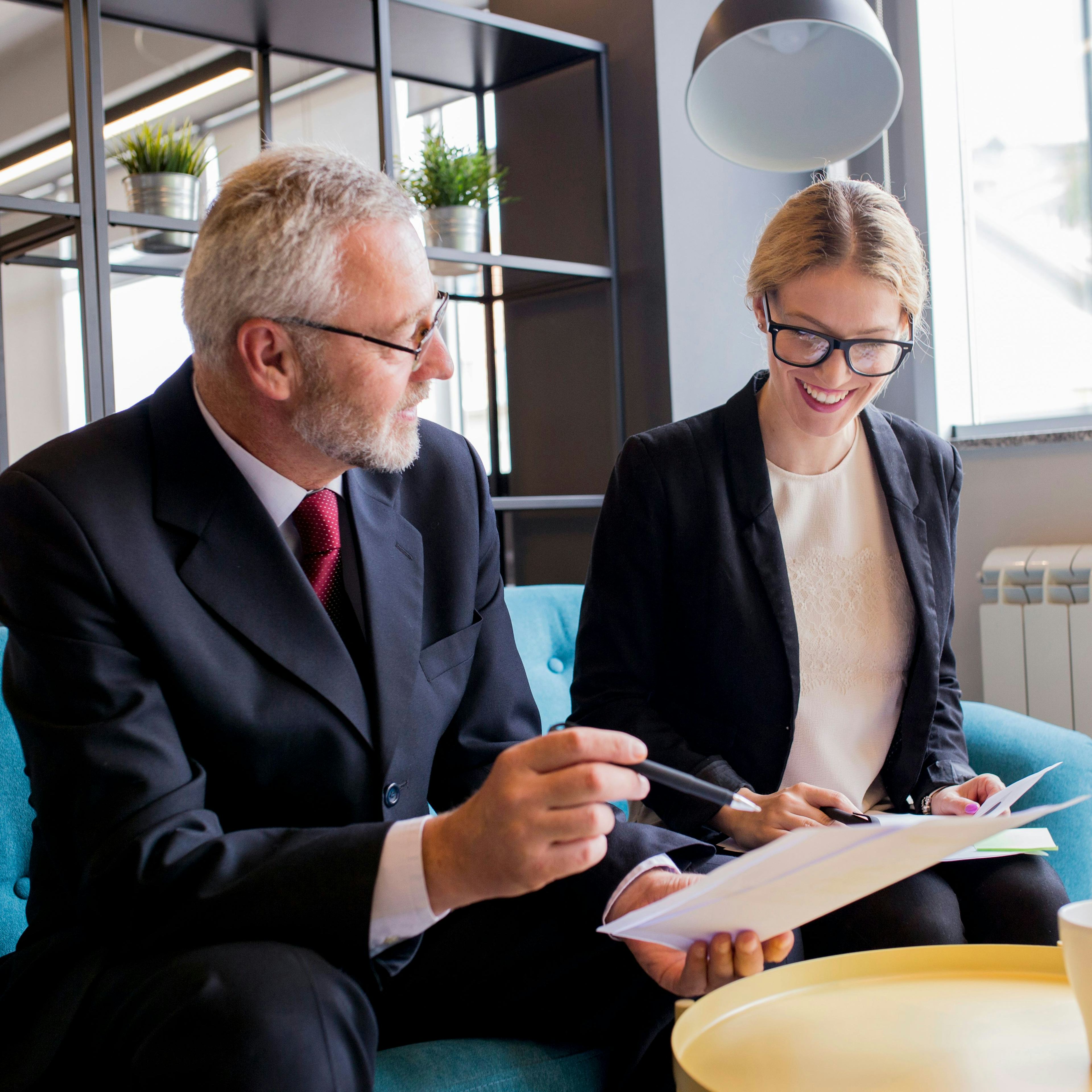 professional businesspeople smiling and discussing the content of a paper being held