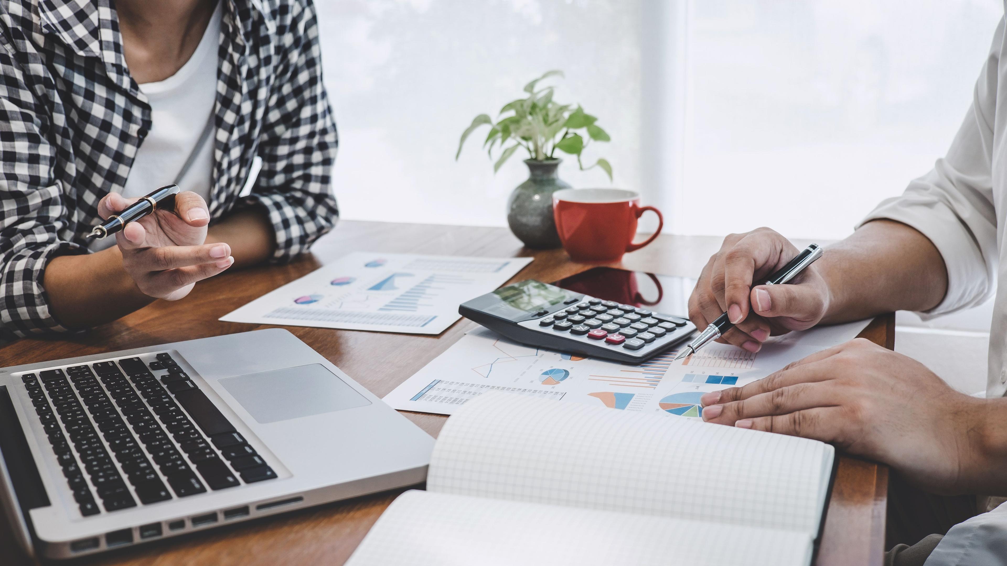 two people working on financial management info on sheets of paper