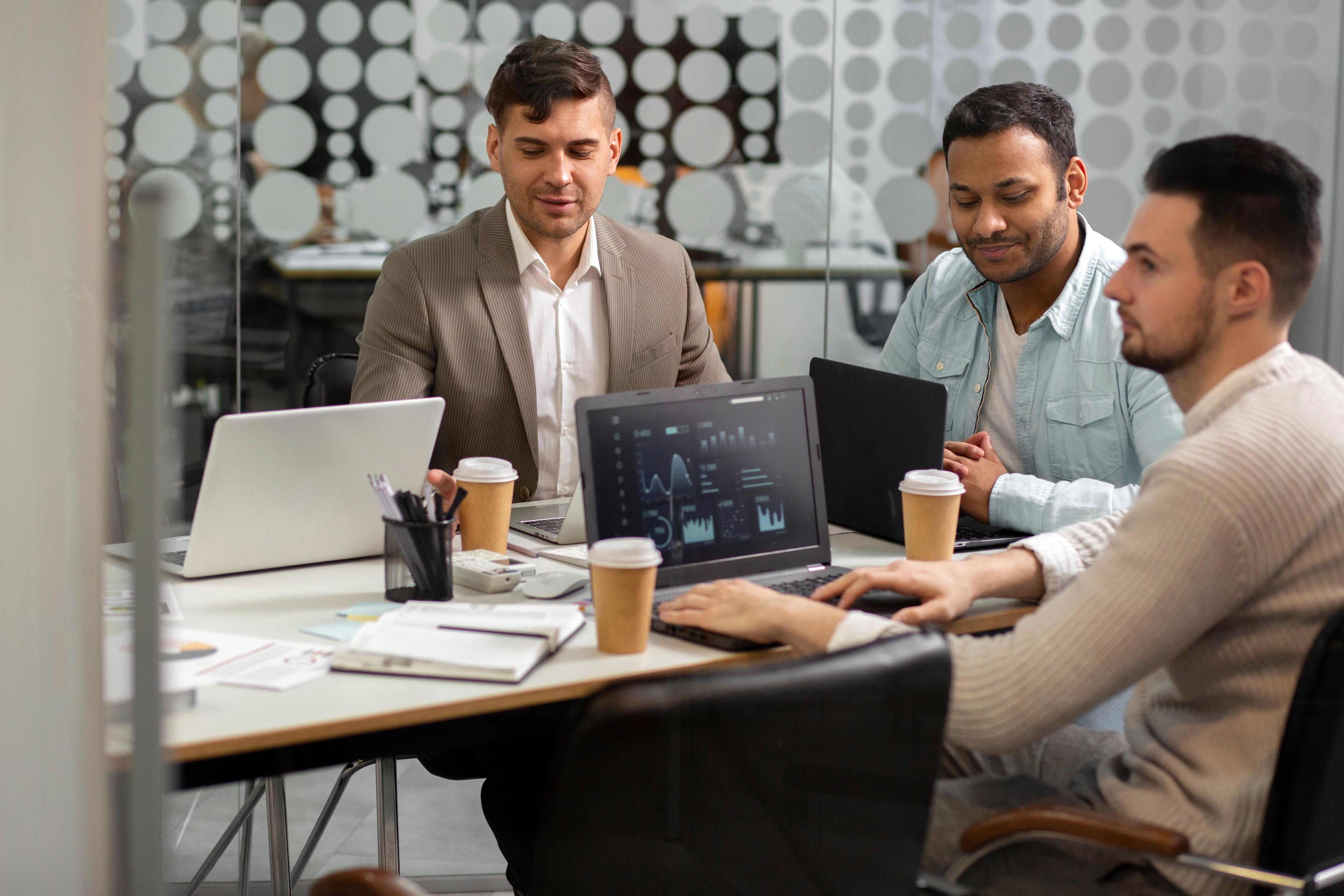 3 men sitting at meeting with their own laptops