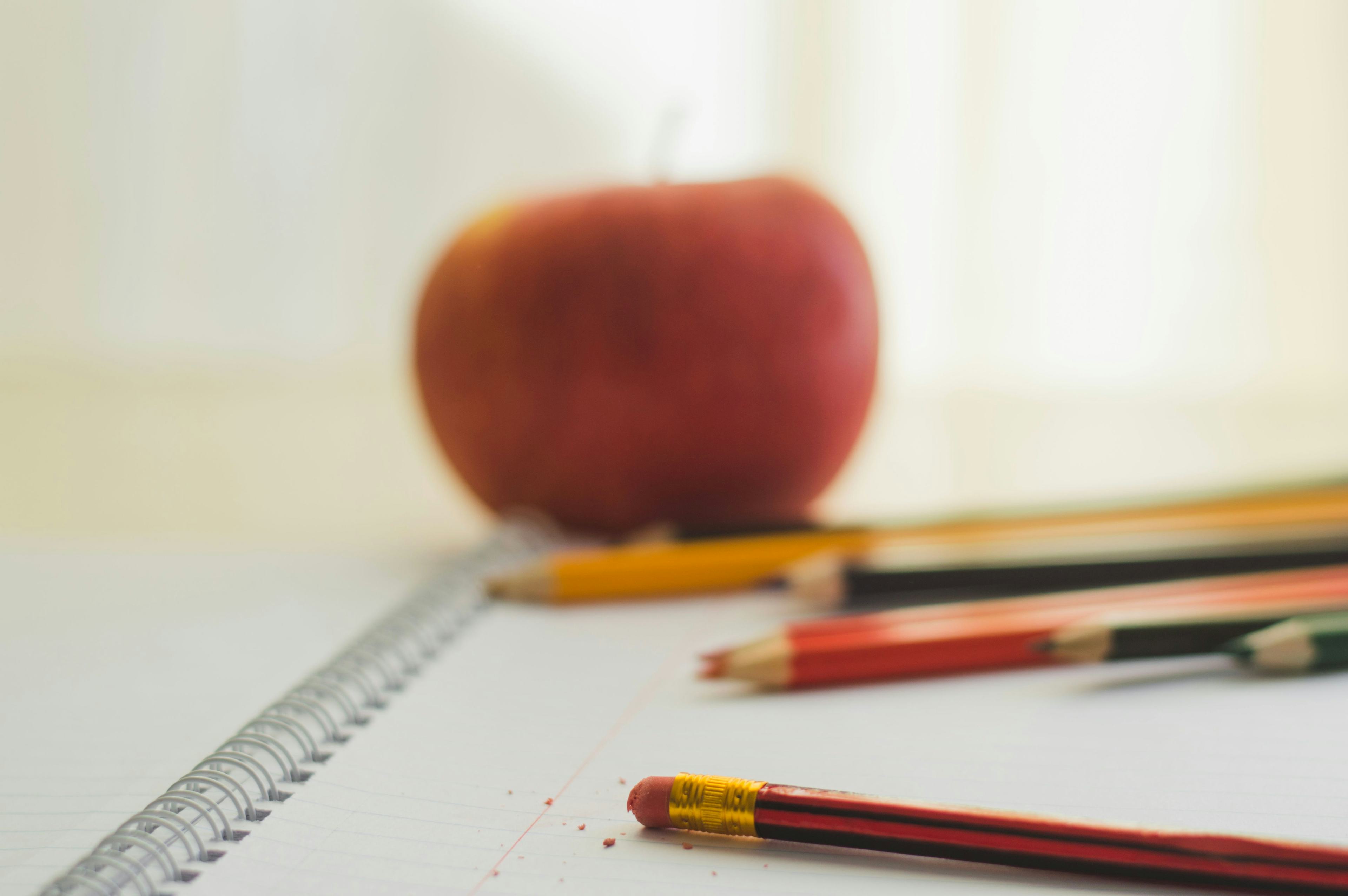 Close up of notebook, apple, and pencils