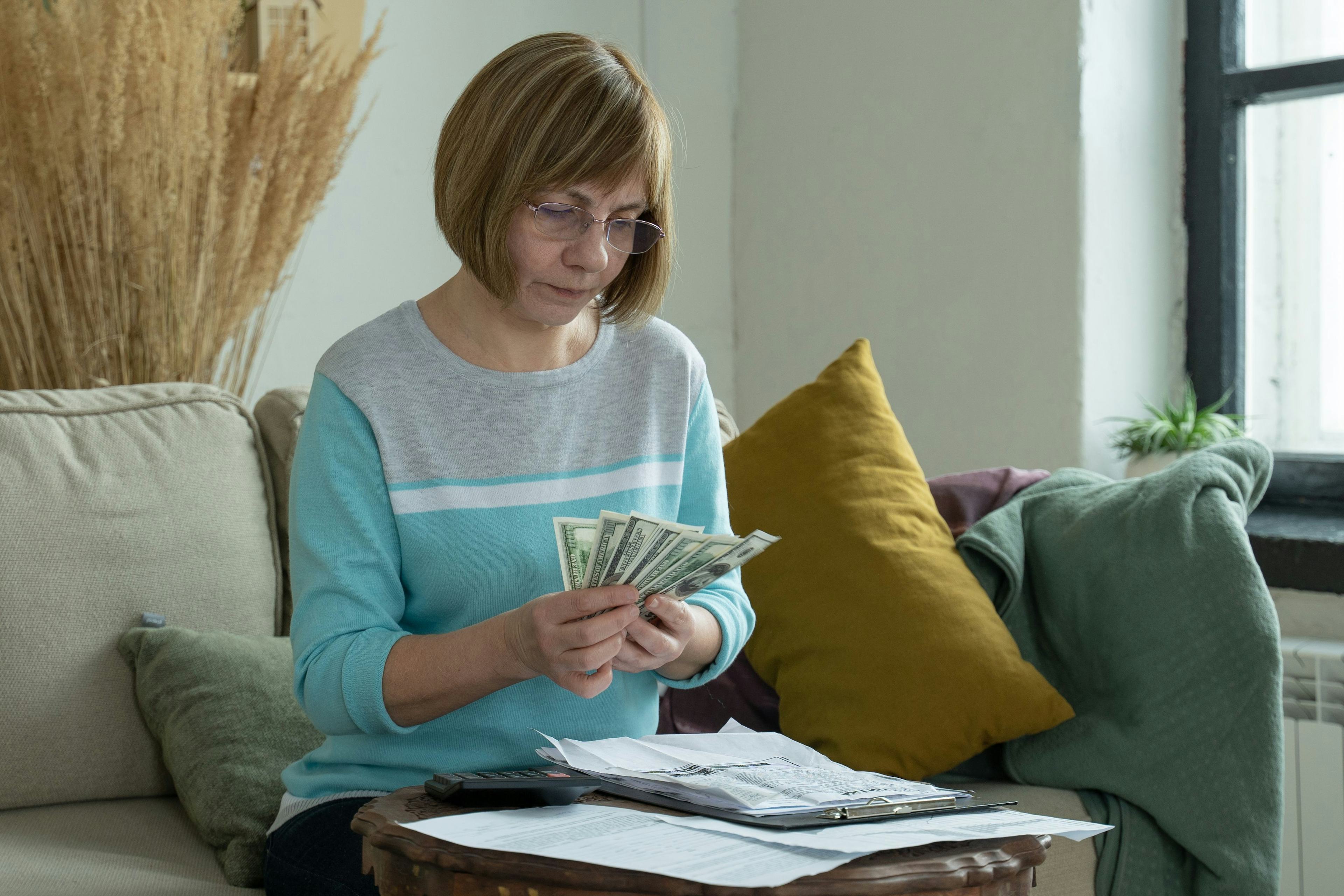 Senior mature woman using calculator holding paper bill calculating money budget tax