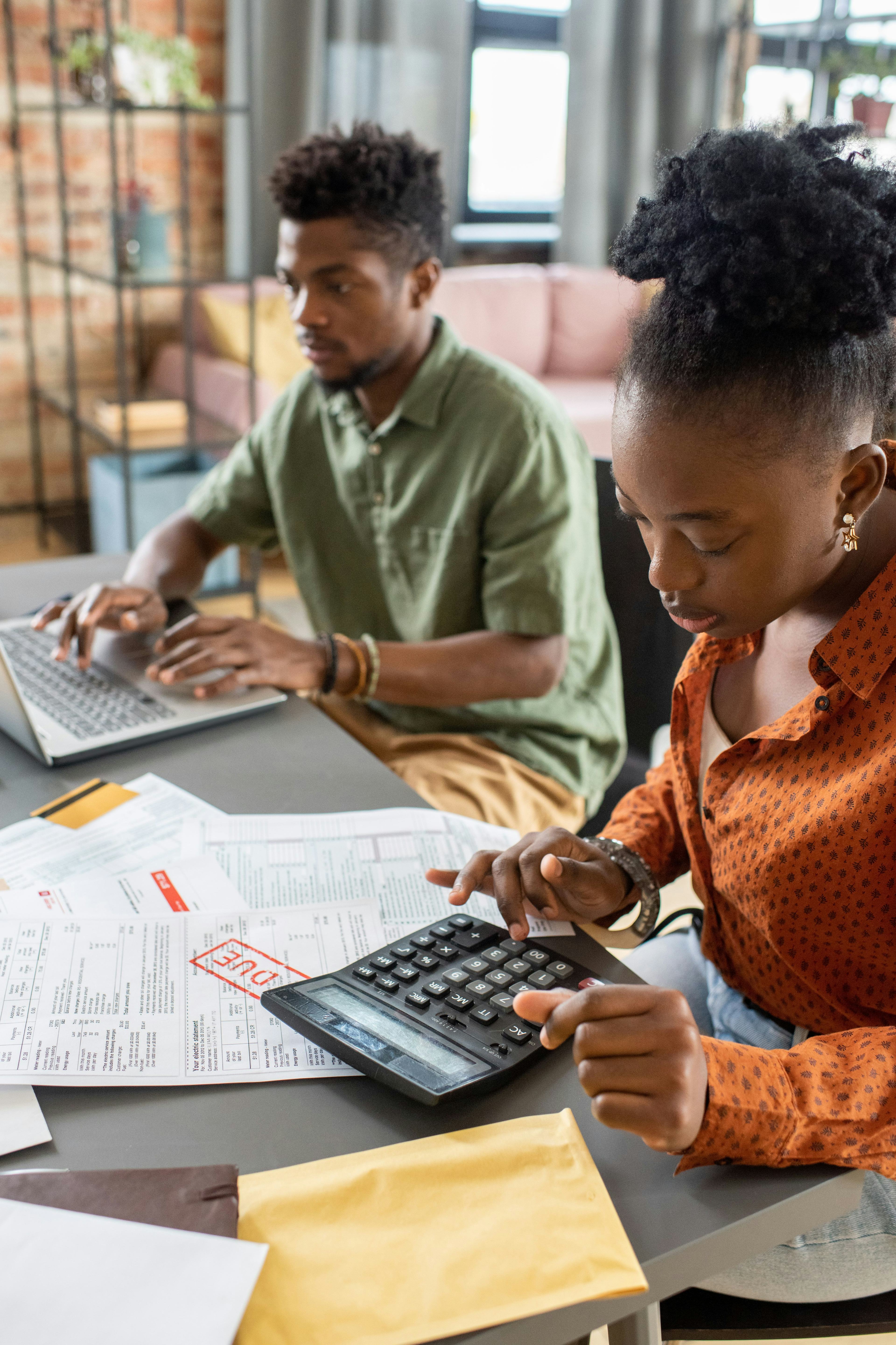 Focused young african american couple sitting at table with papers and analyzing costs