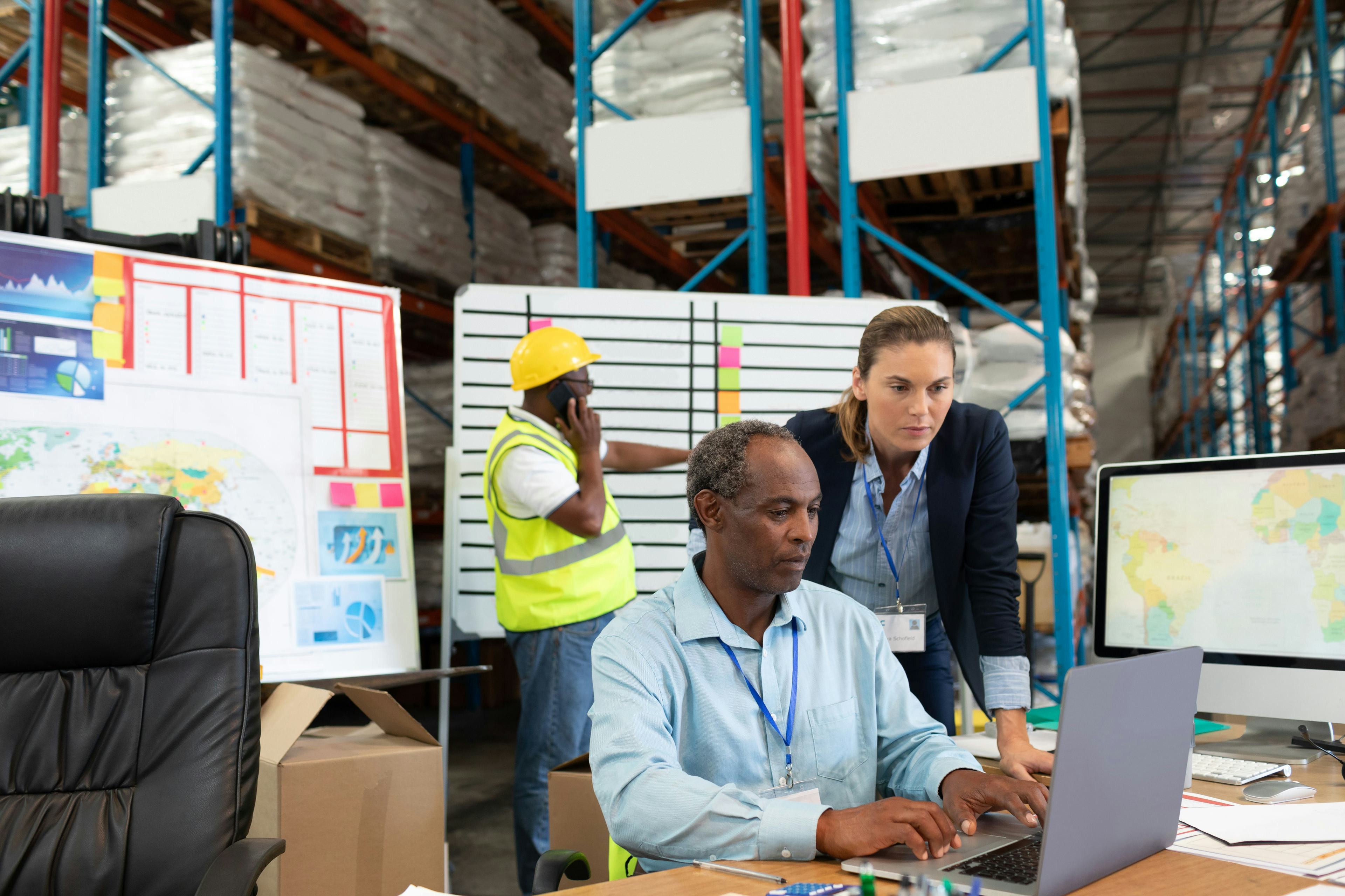 coworkers viewing data on laptop in warehouse