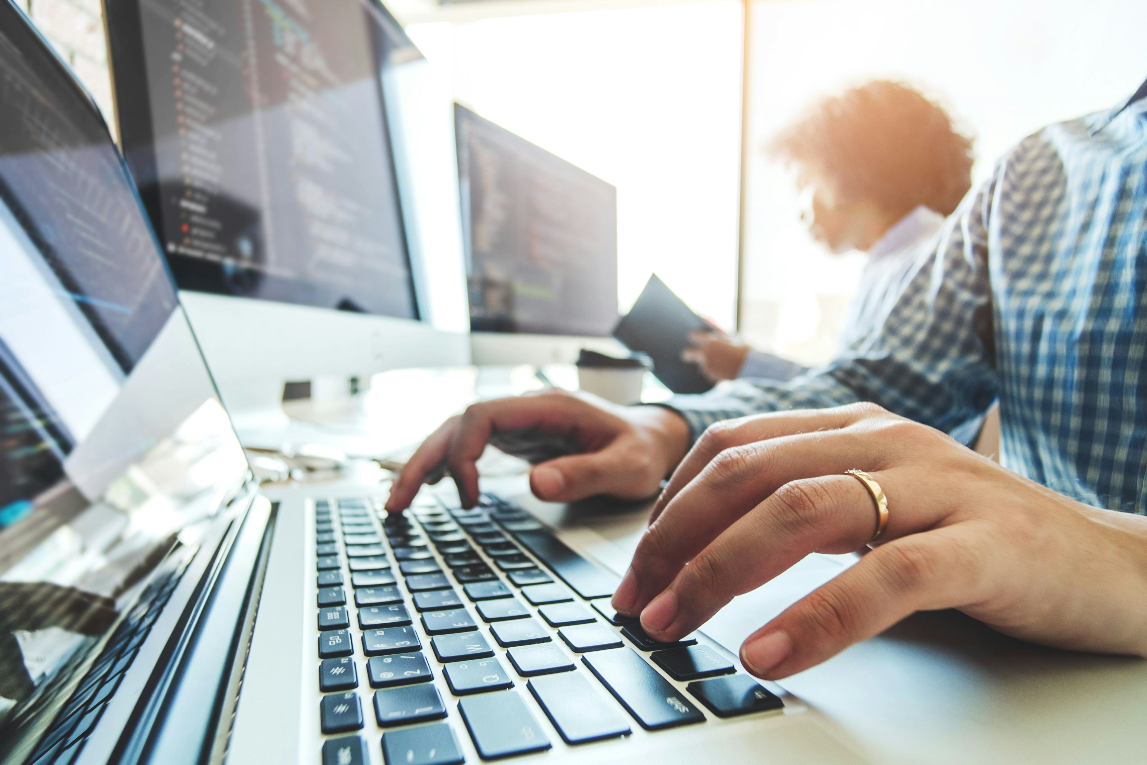 people typing code out for software development on open laptops