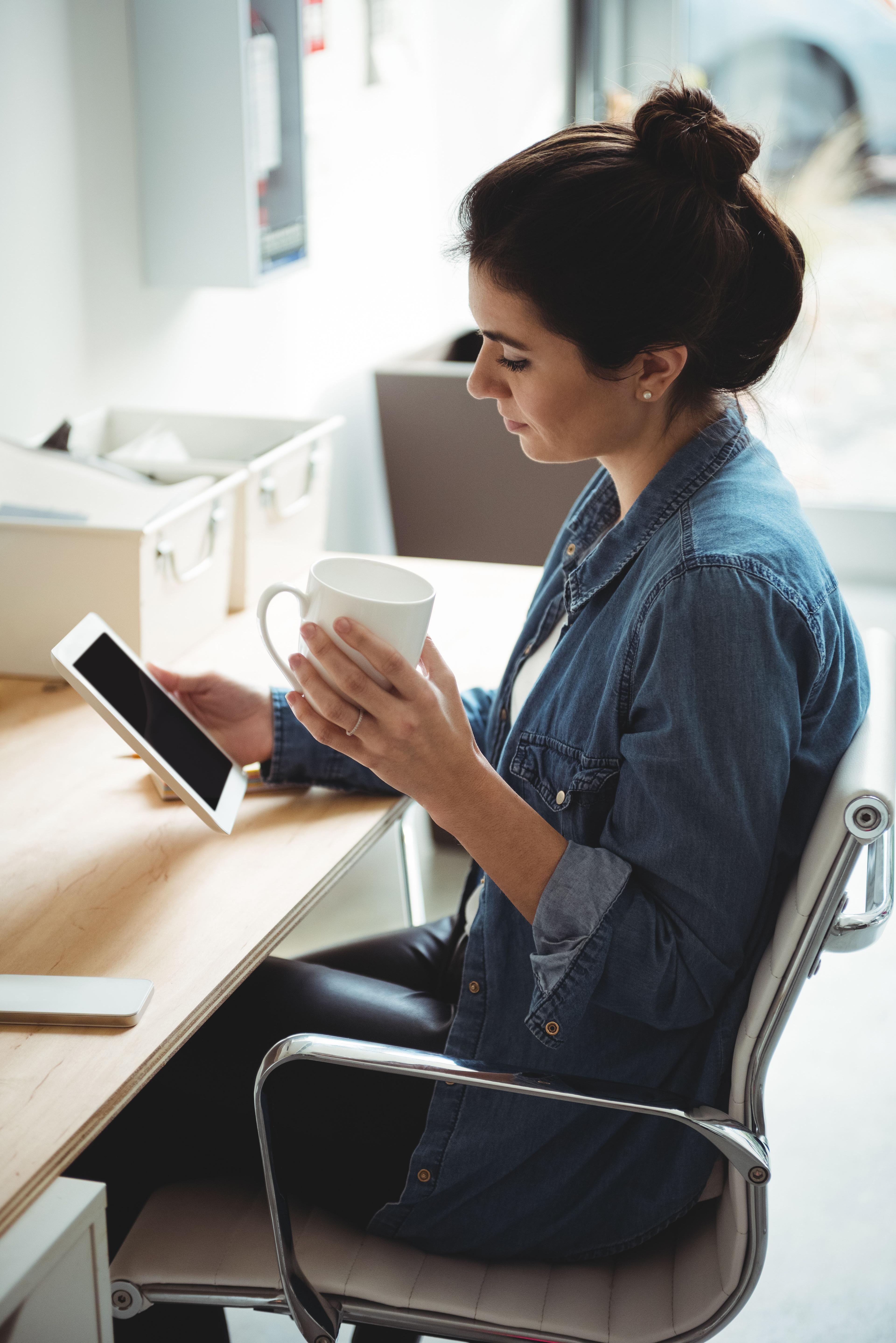 Business executive using digital tablet while having cup of coffee