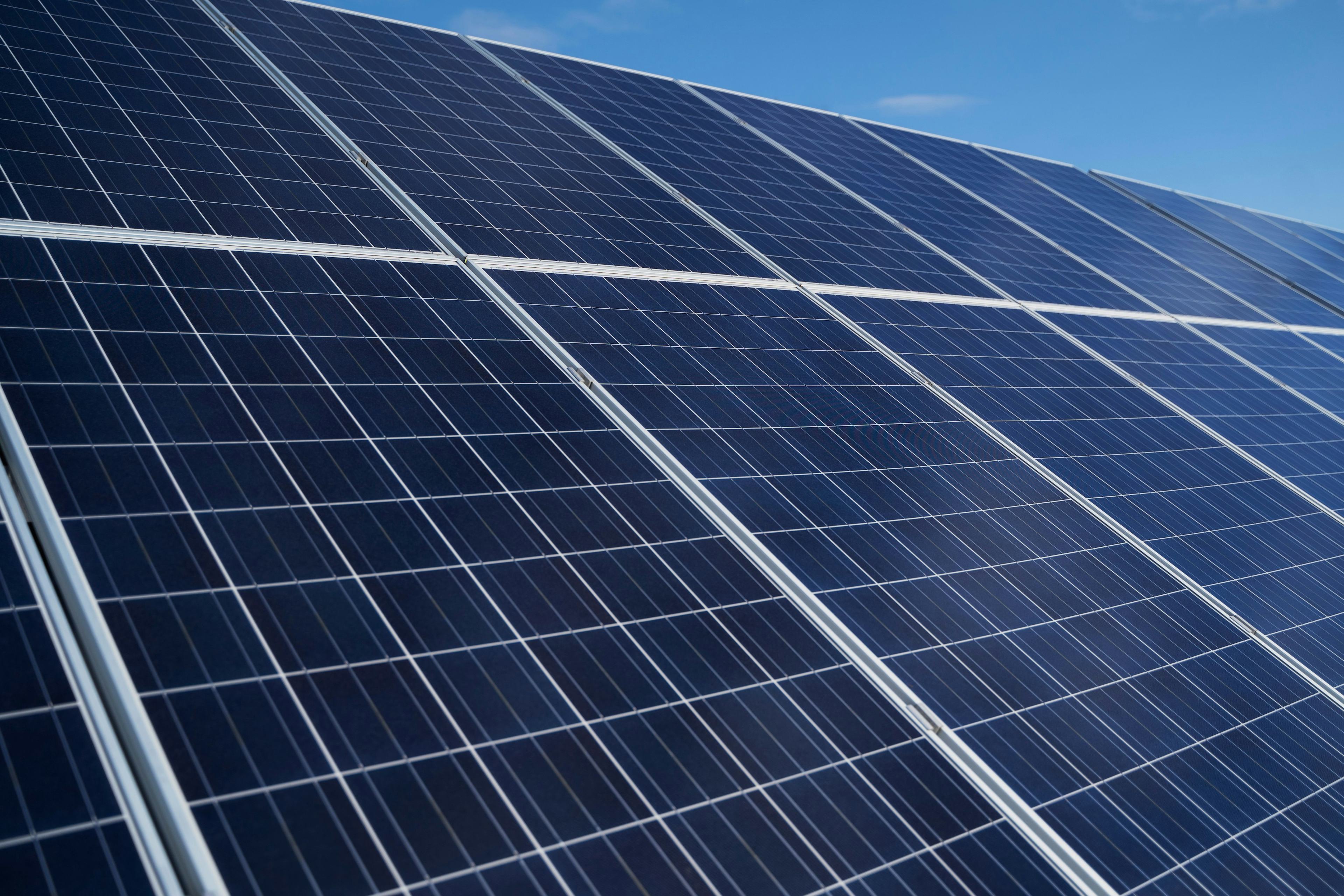 Closeup of surface of blue photovoltaic solar panels mounted on building roof for producing clean ecological electricity. Production of renewable energy concept.