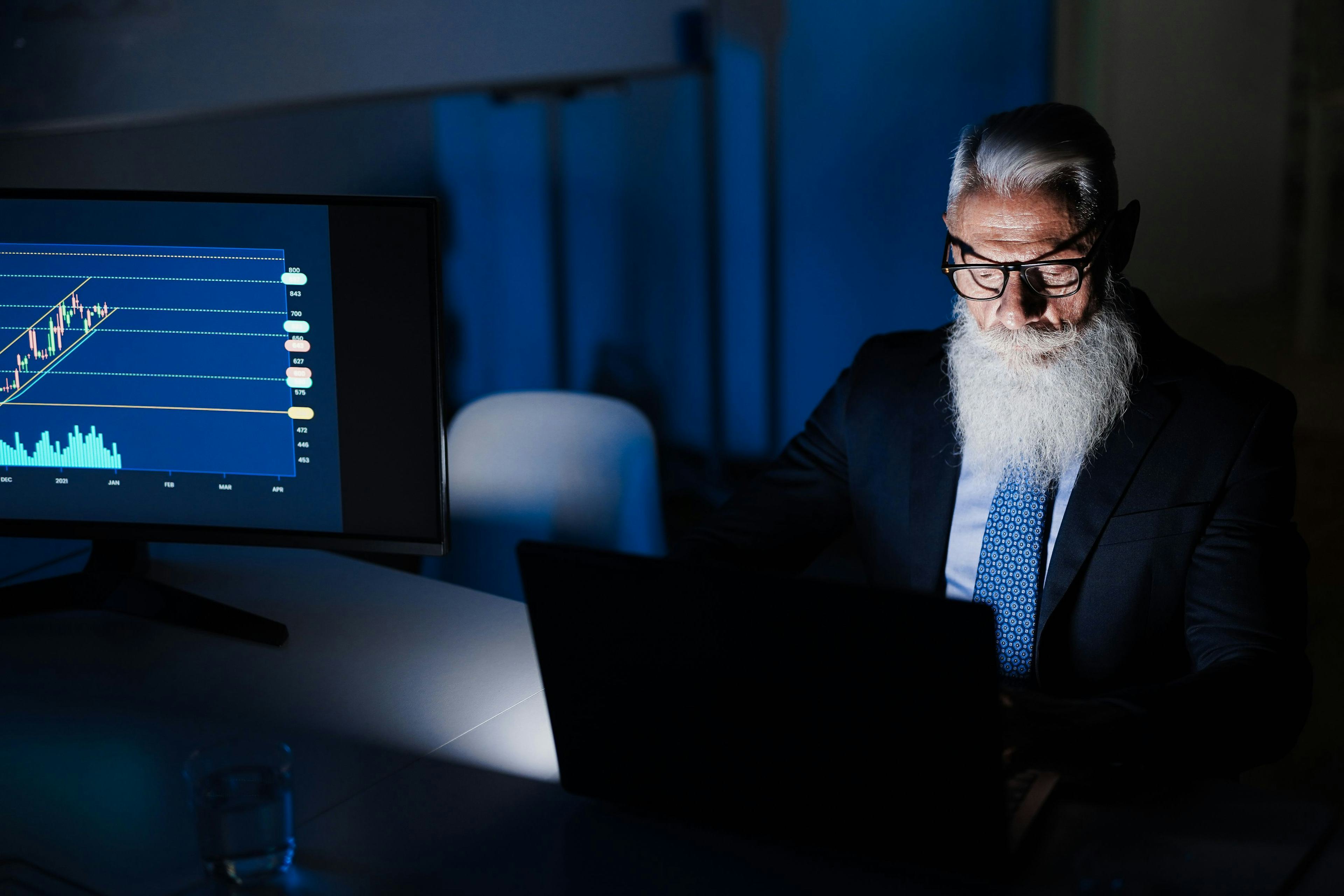 Business man looking at computer with a graph behind him