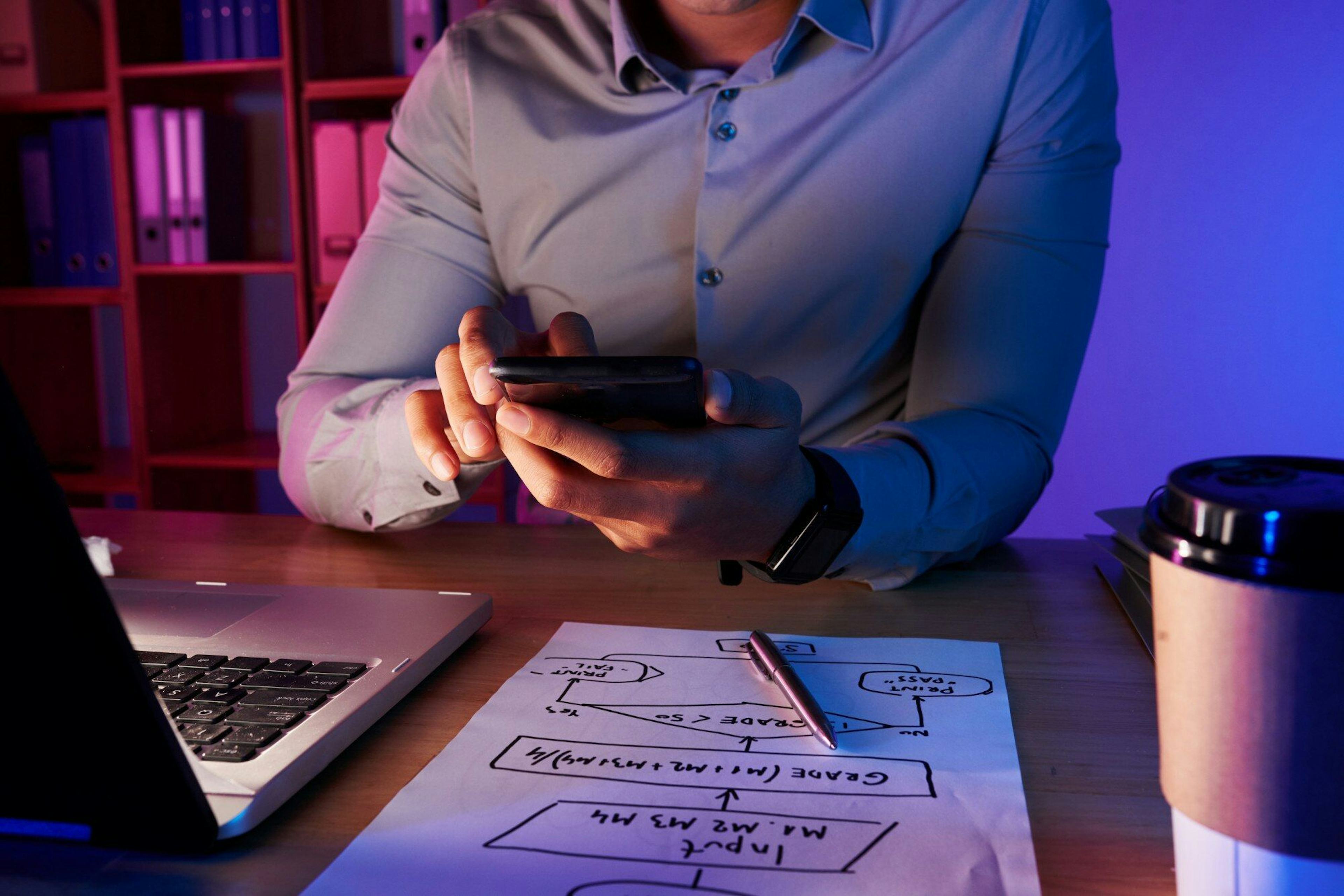 man working with user flow diagram while holding phone