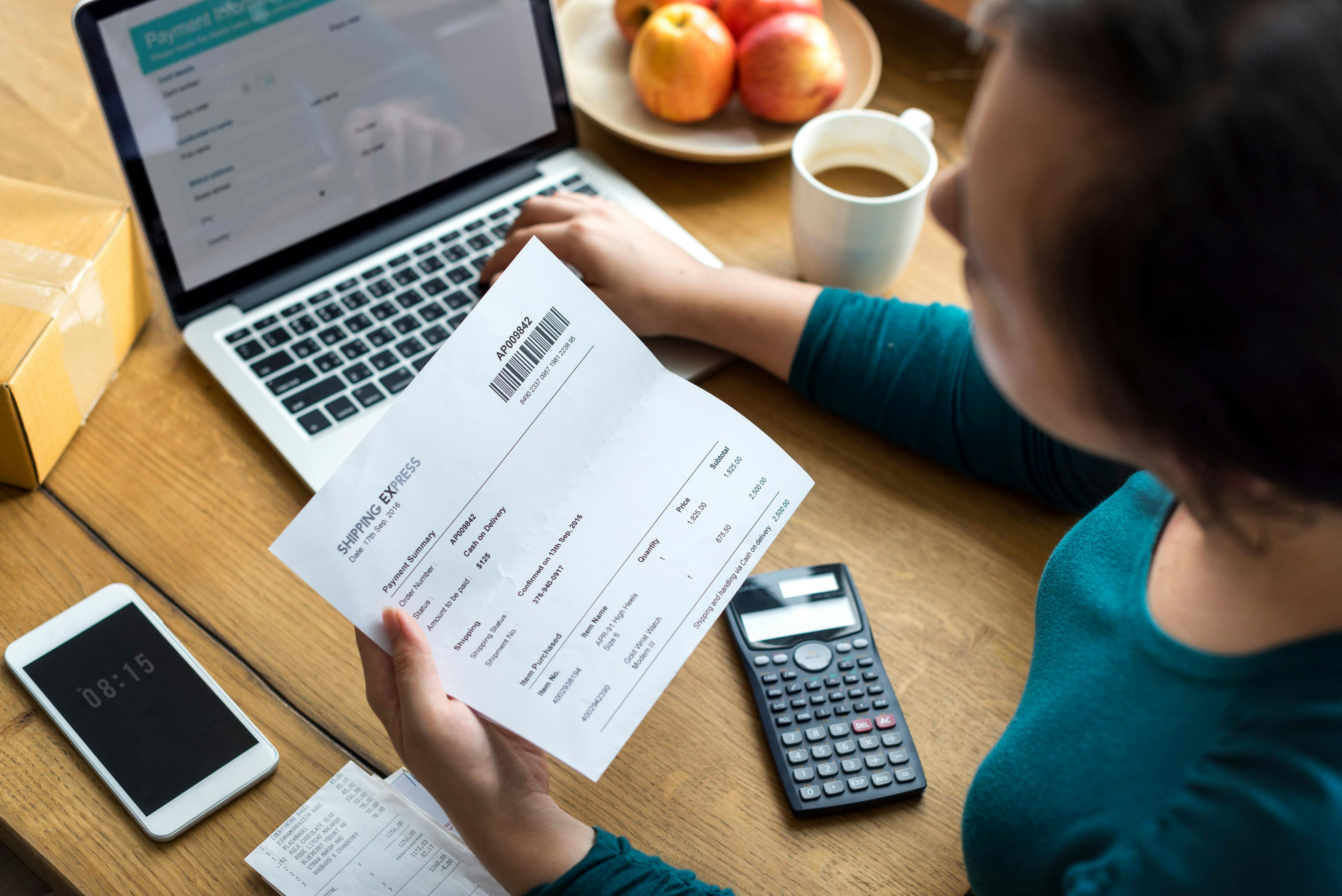 woman viewing a paper receipt with open laptop in front of her