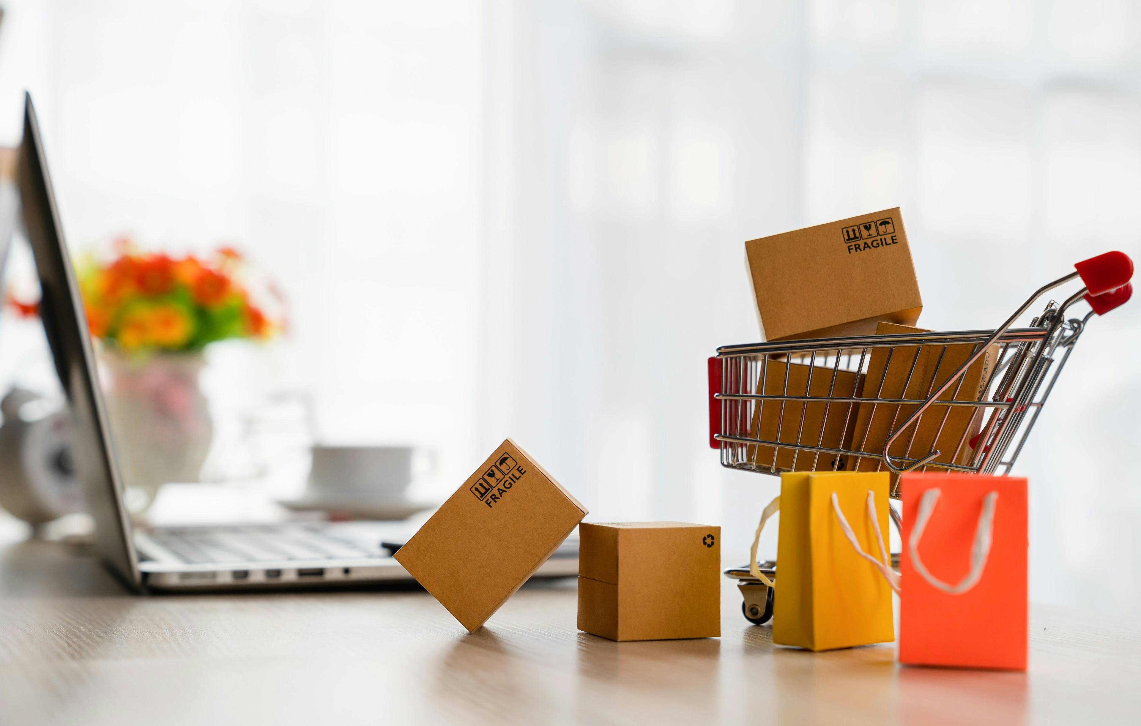 a small shopping cart filled with packages by a laptop