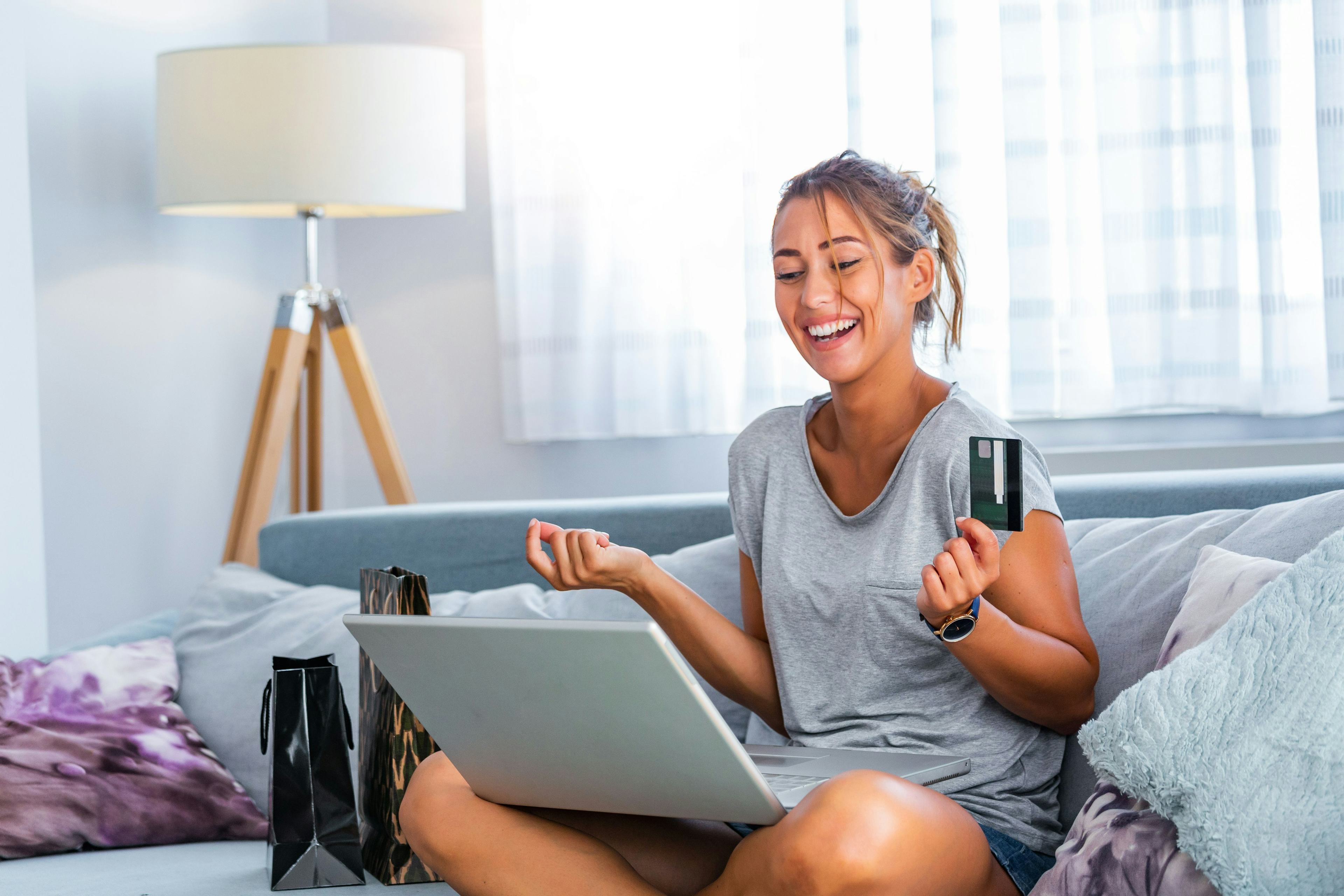 smiling woman holding card and doing online shopping at home