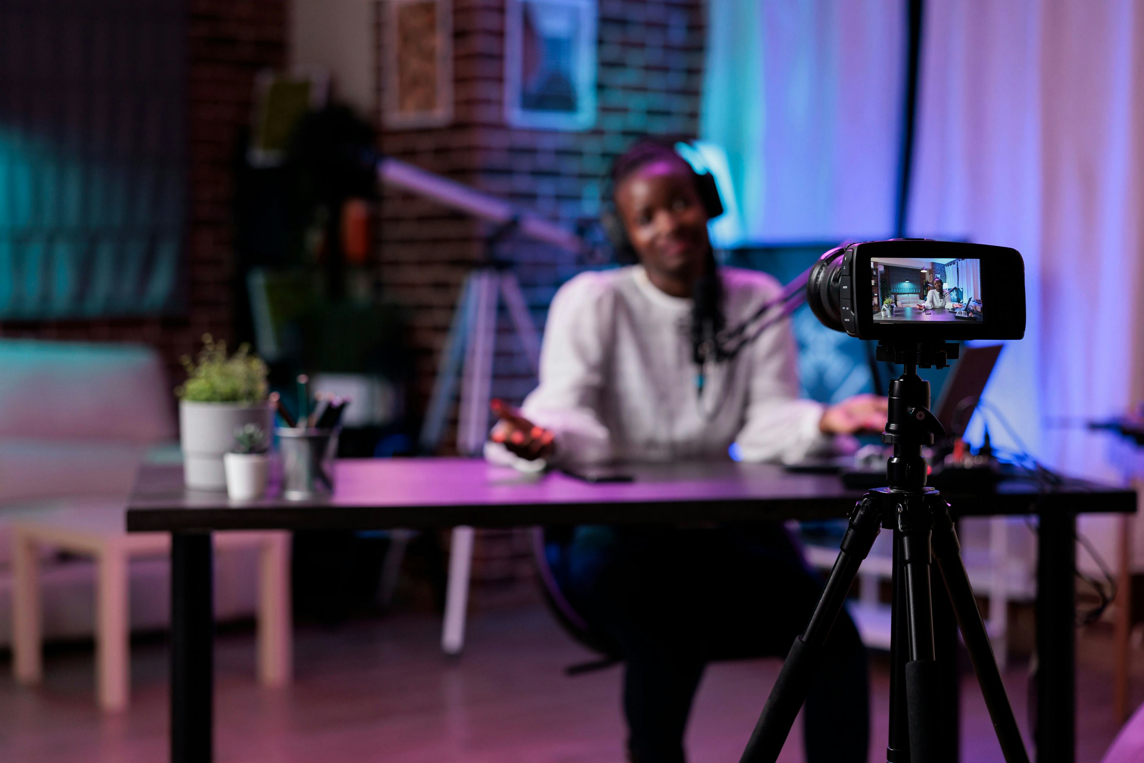 Female content creator sitting at table with camera on tripod in front of her