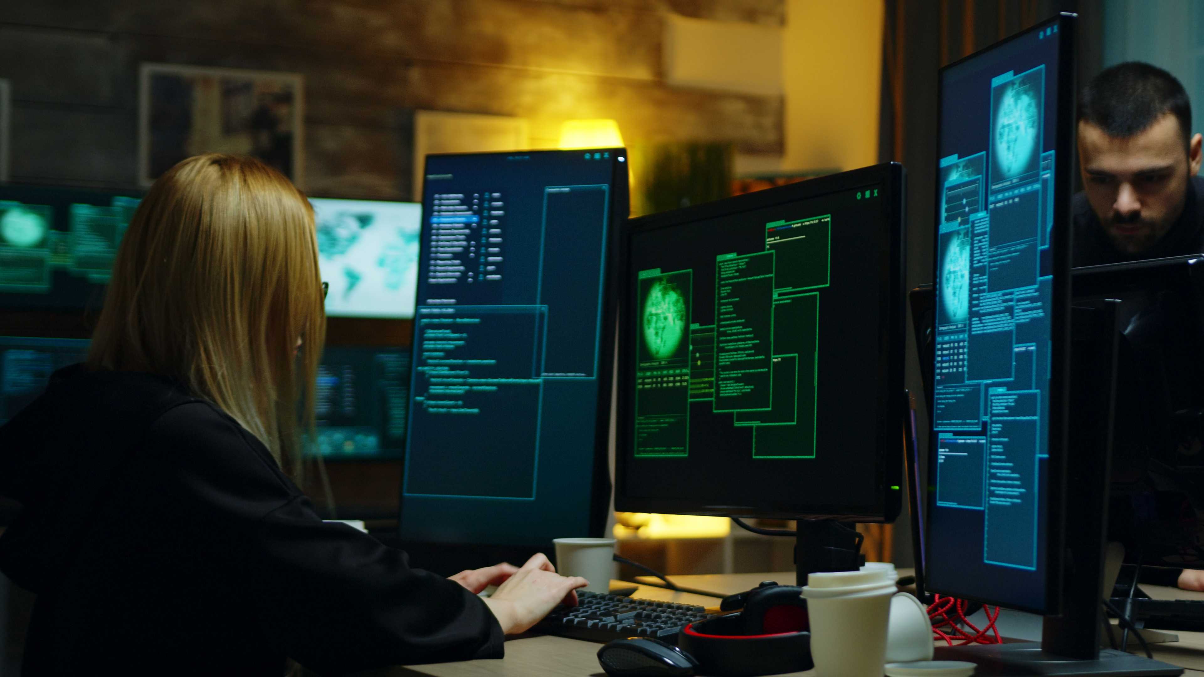 woman and man in office working on computer monitors in dimly lit environment