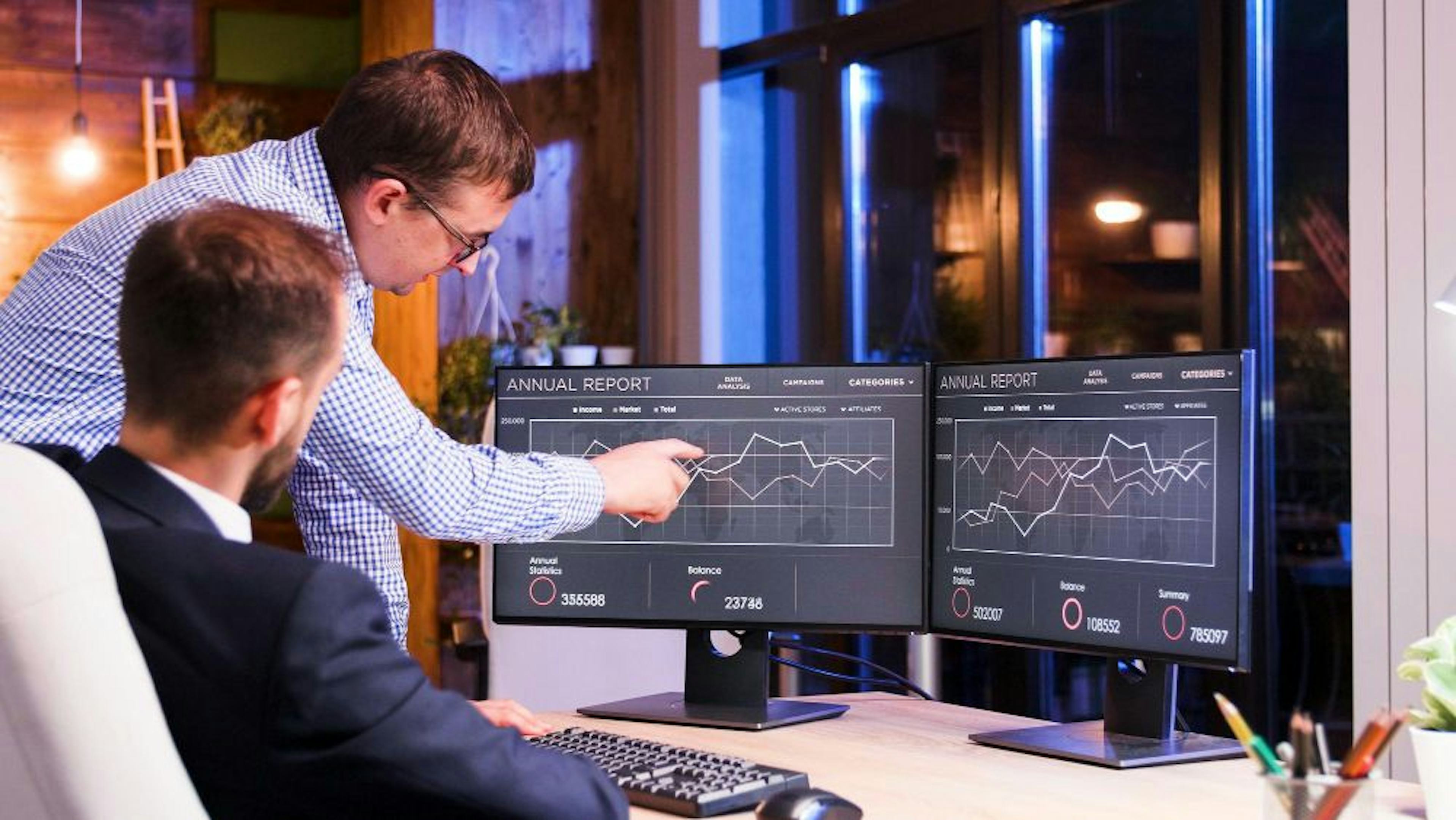 Two colleagues discussing graphs on computuer screen