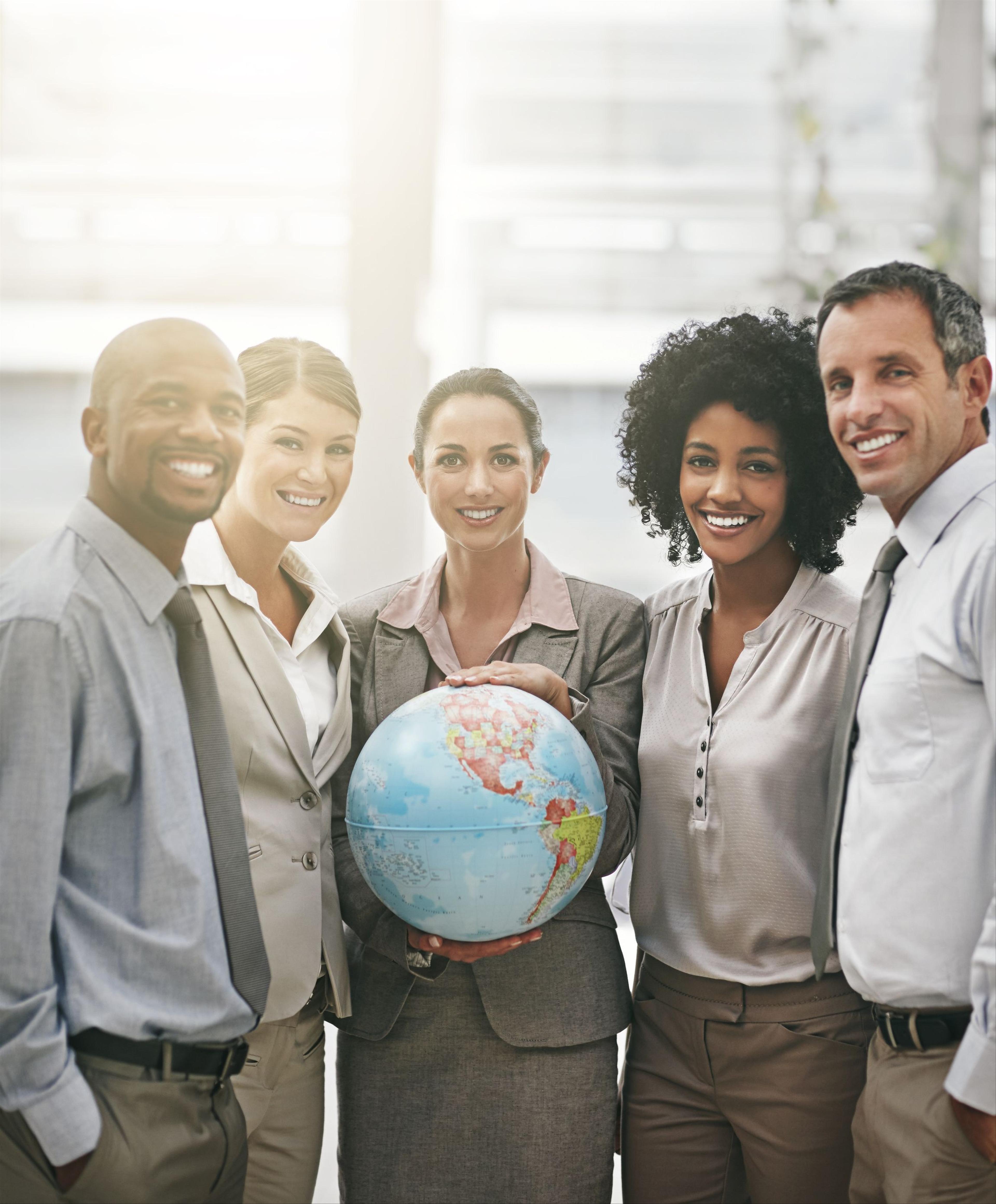 multiracial group of work professionals holding a globe of earth and smiling at camera