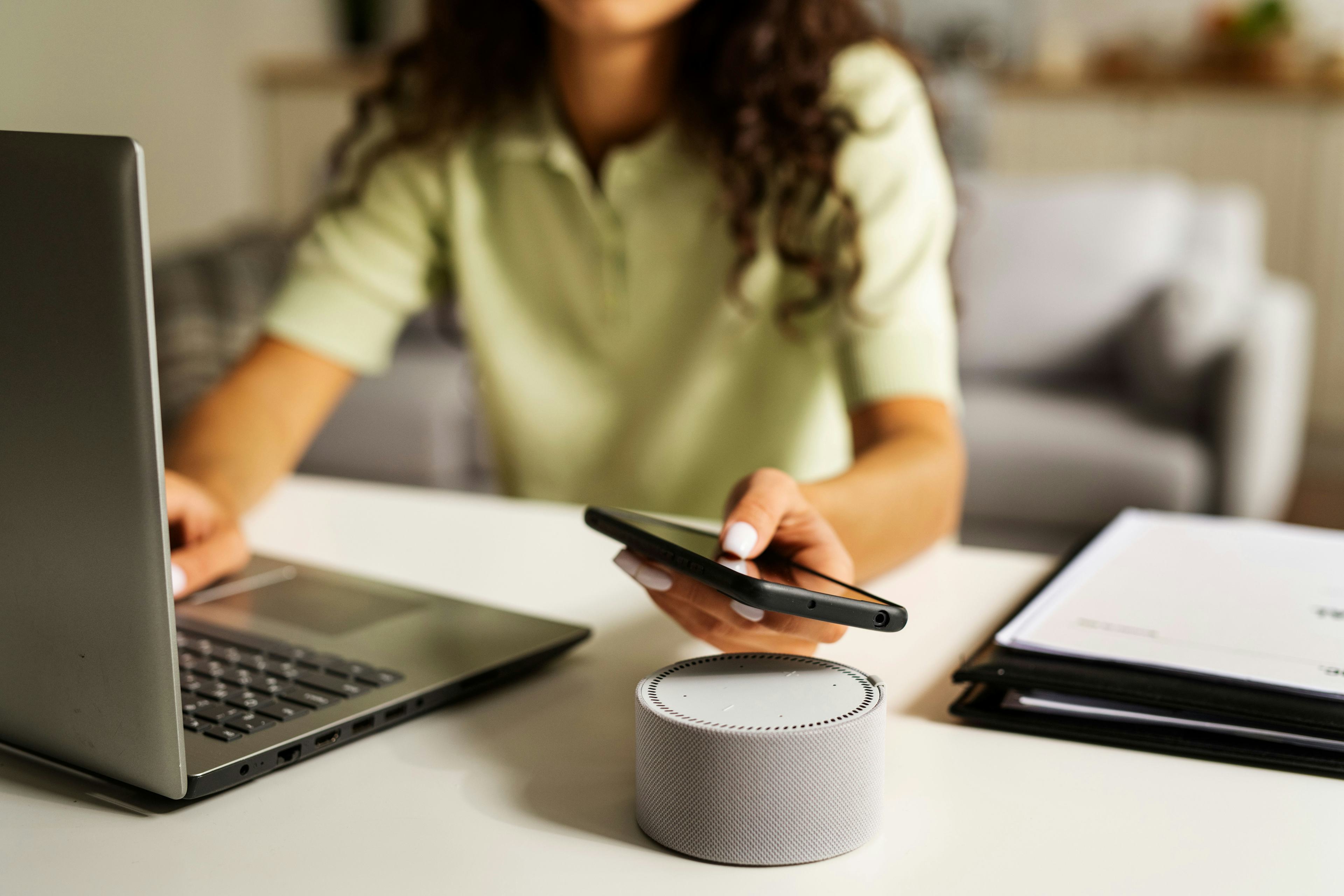 Side view woman working on laptop with voice assistant device