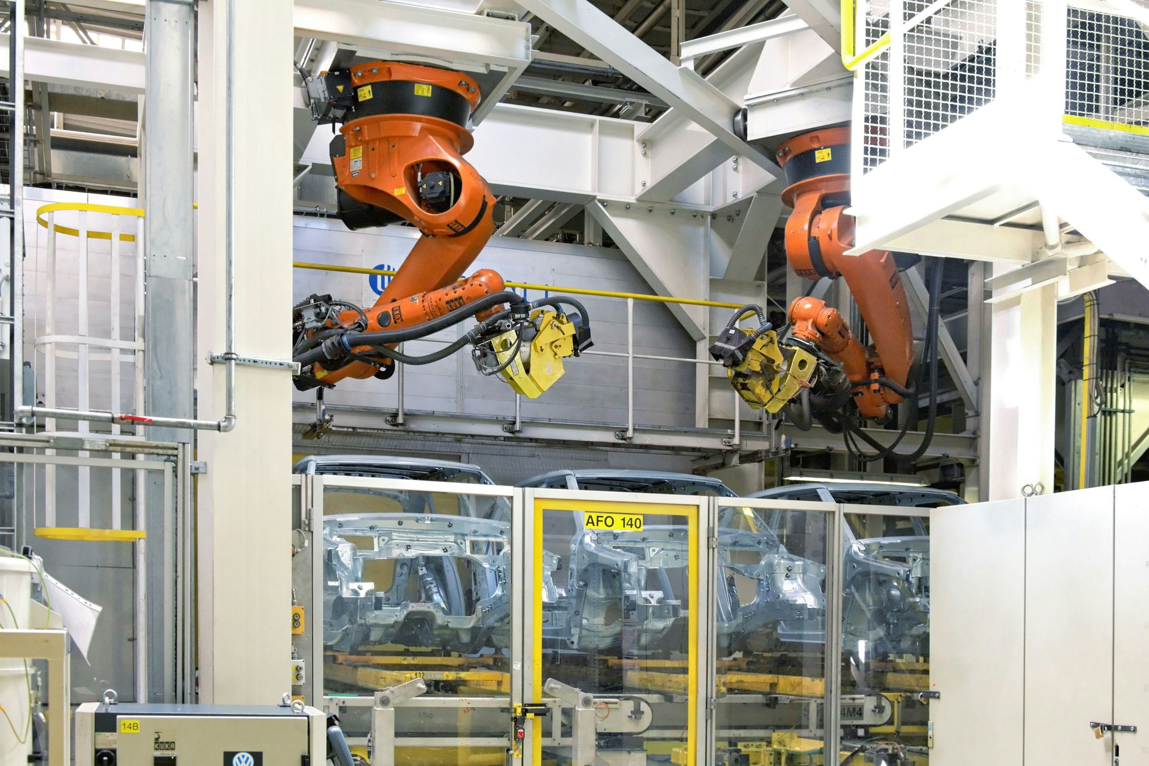 two industrial, orange robotic arms resting idle above containers