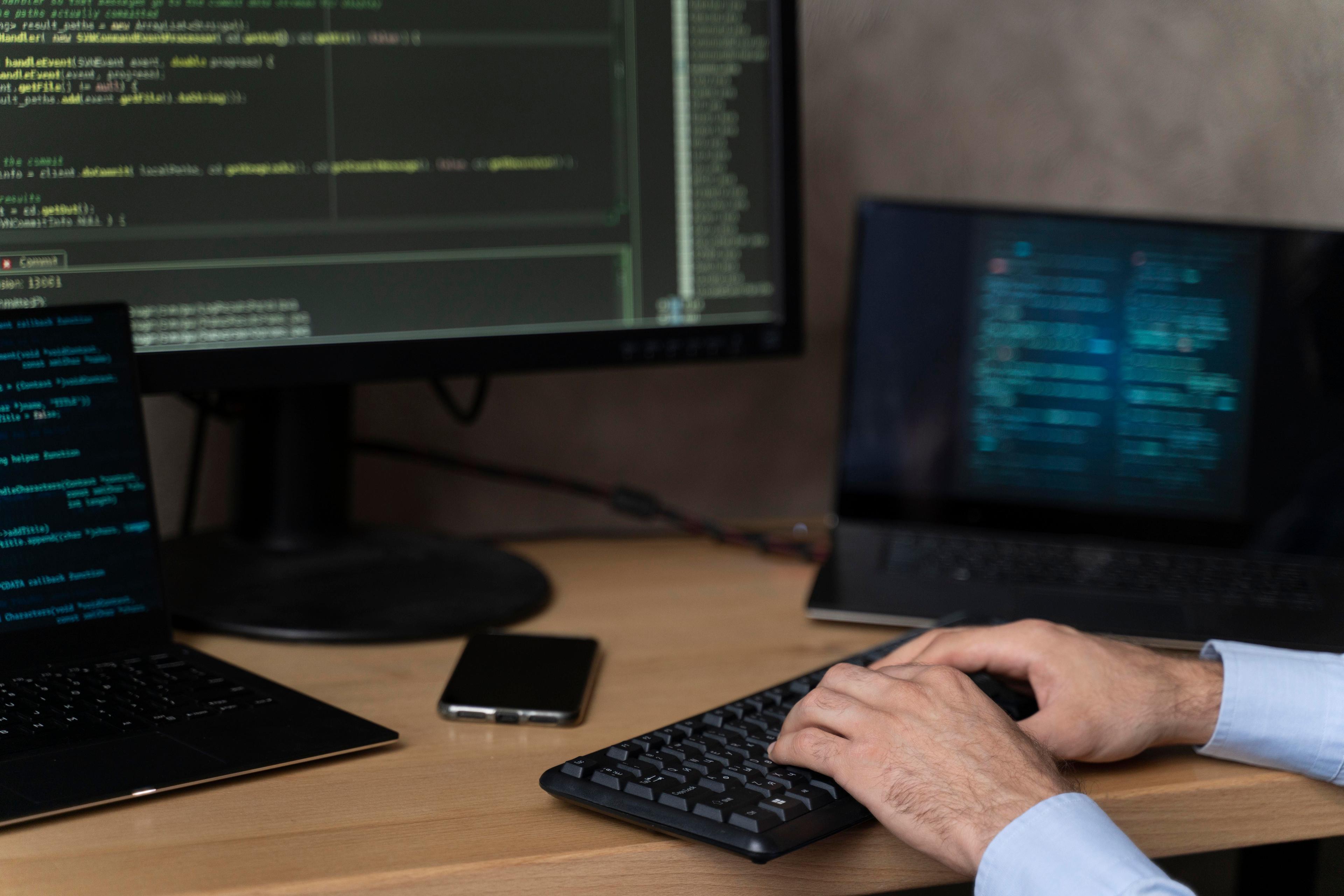 man typing code onto a desktop computer