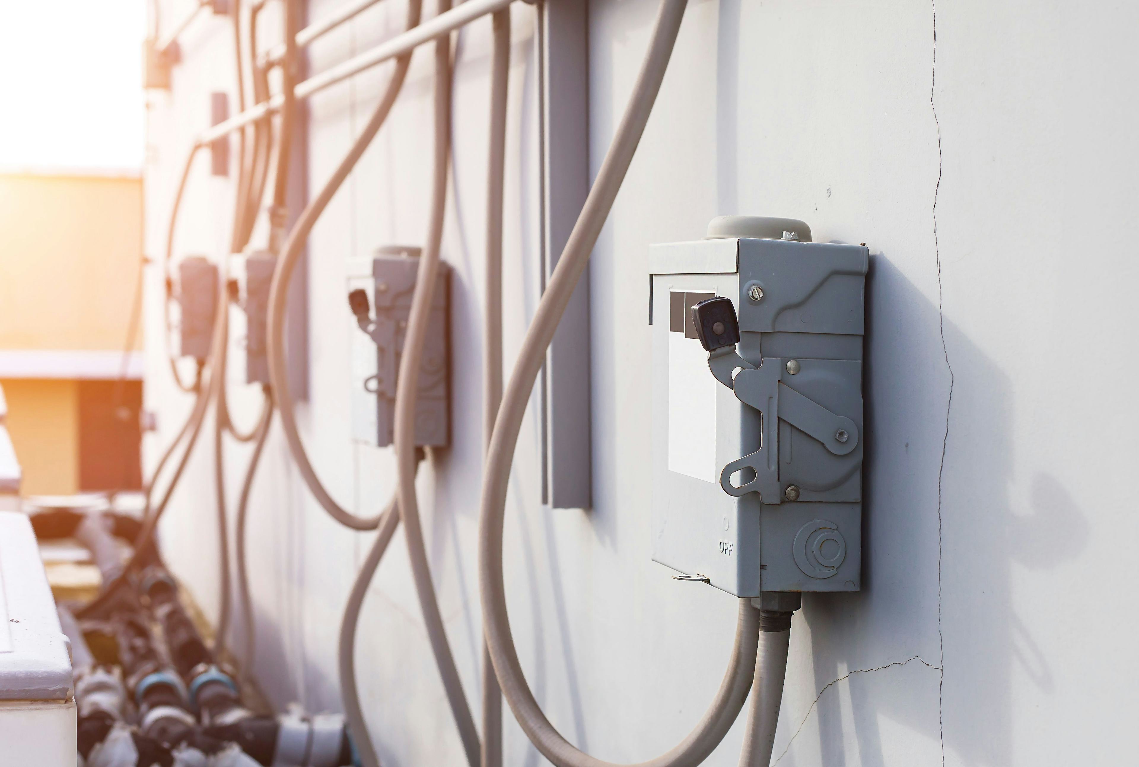 power boxes with thick white wiring attached to white concrete wall