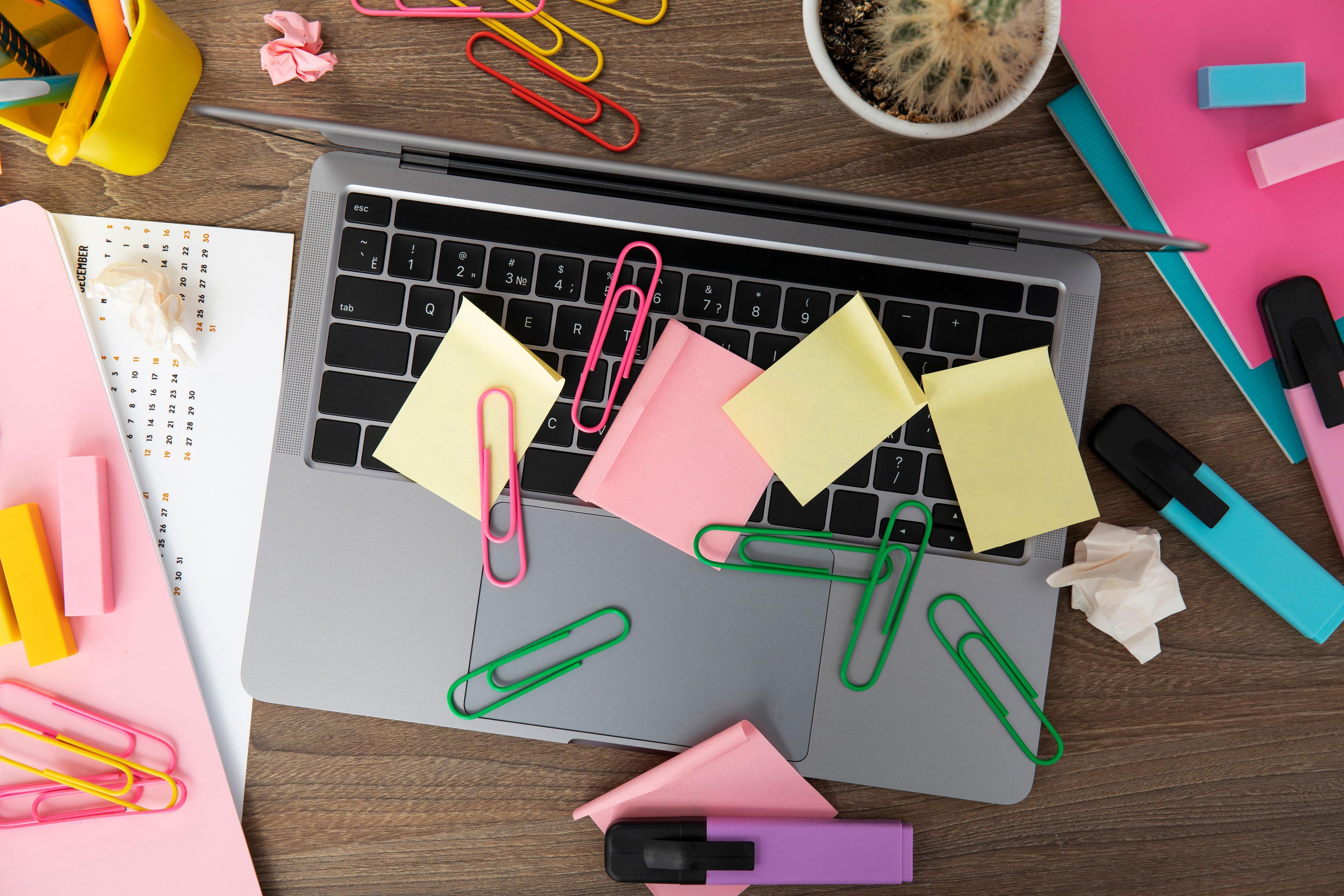 laptop with sticky notes and paperclips on keyboard