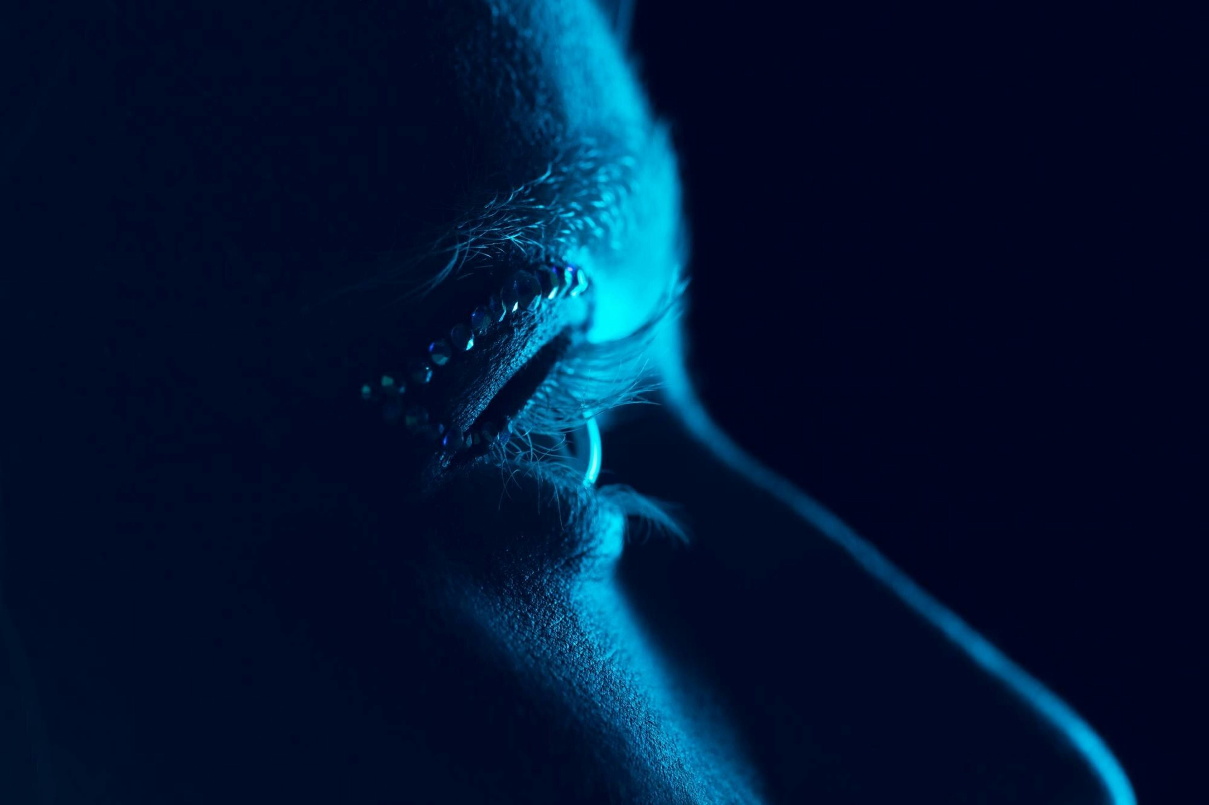 side profile of woman's eyes in blue lighting