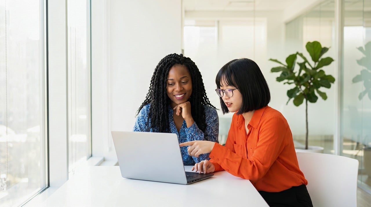 Two colleagues mentoring and learning together at laptop